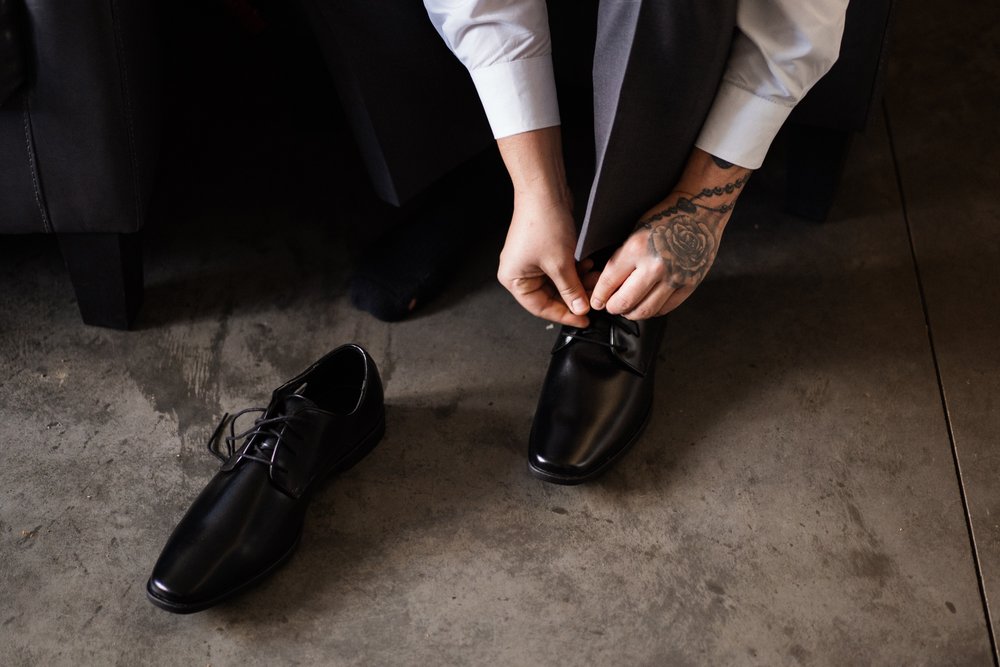 Groom ties shoes at Camelot Ranch.