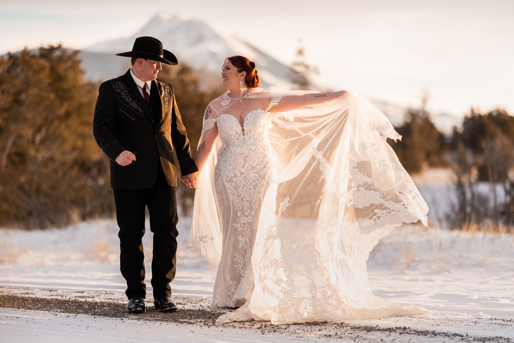 Winter wedding cowboy groom and cowgirl bride walk outside in snow