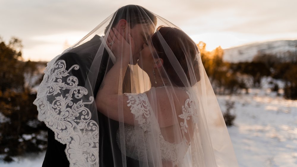 Western newlyweds kiss under the veil.