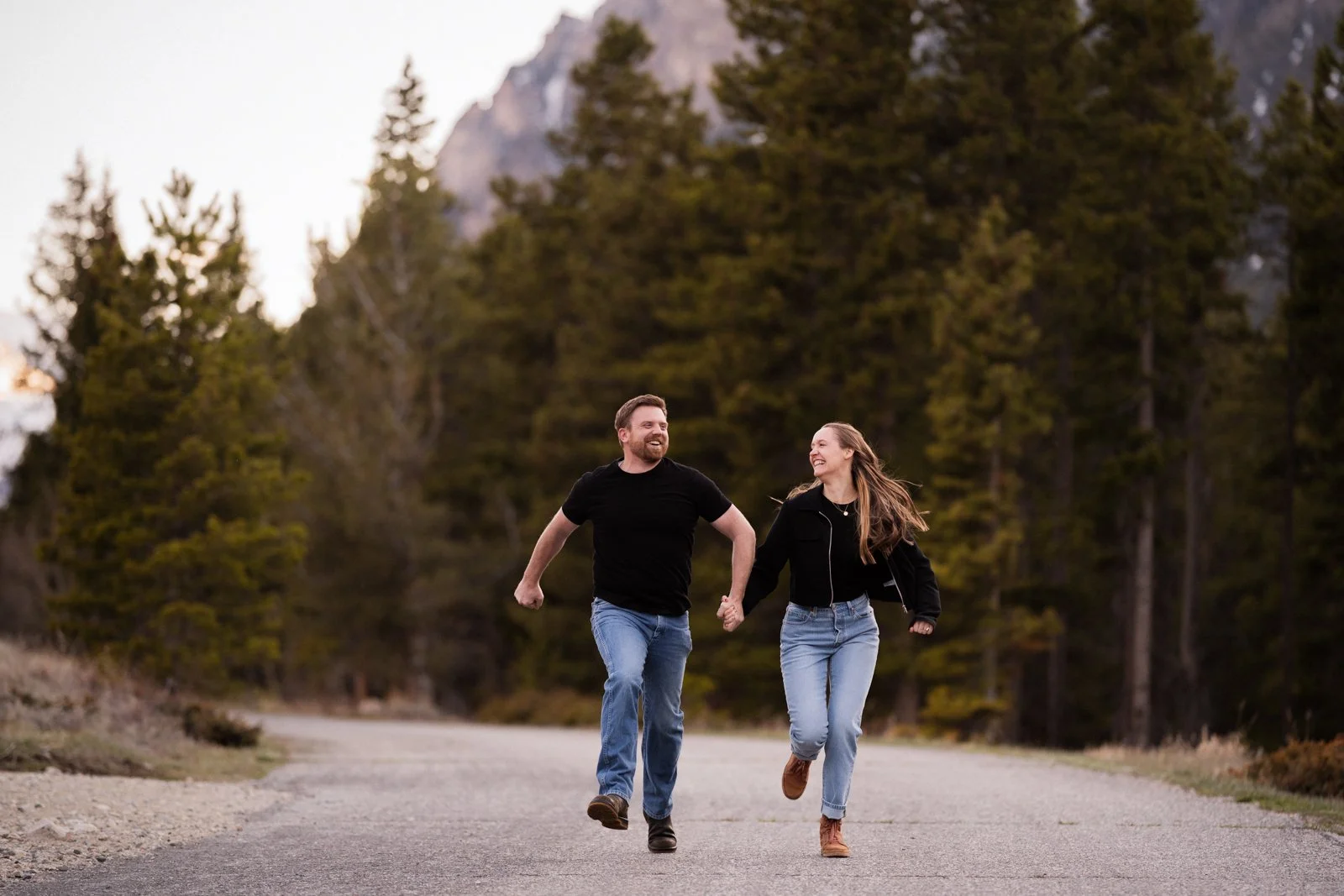 Couple running and laughing together during a candid engagement session near Red Lodge Montana