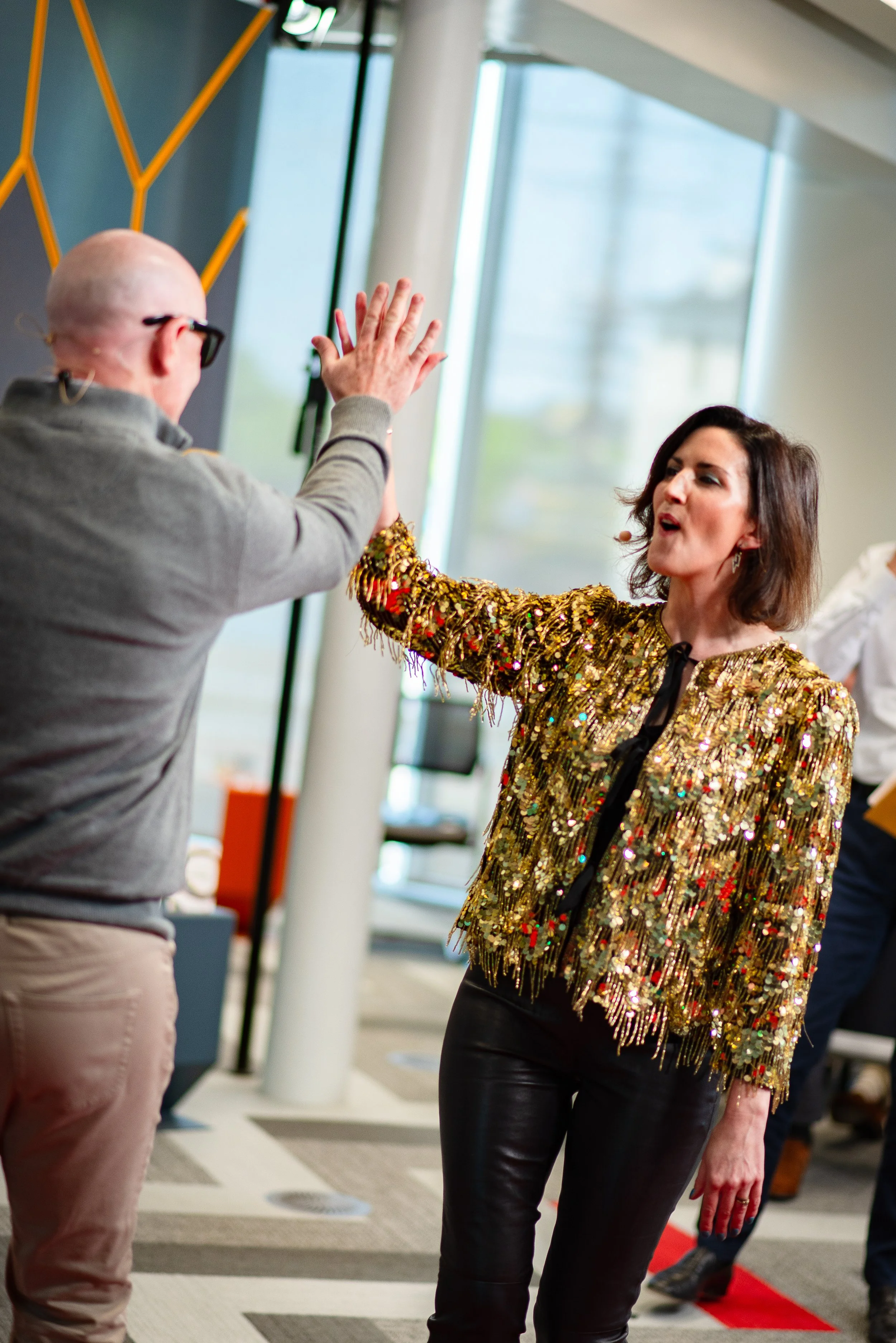 Presenter in glitter jacket high fiving at conference in Amsterdam.jpeg