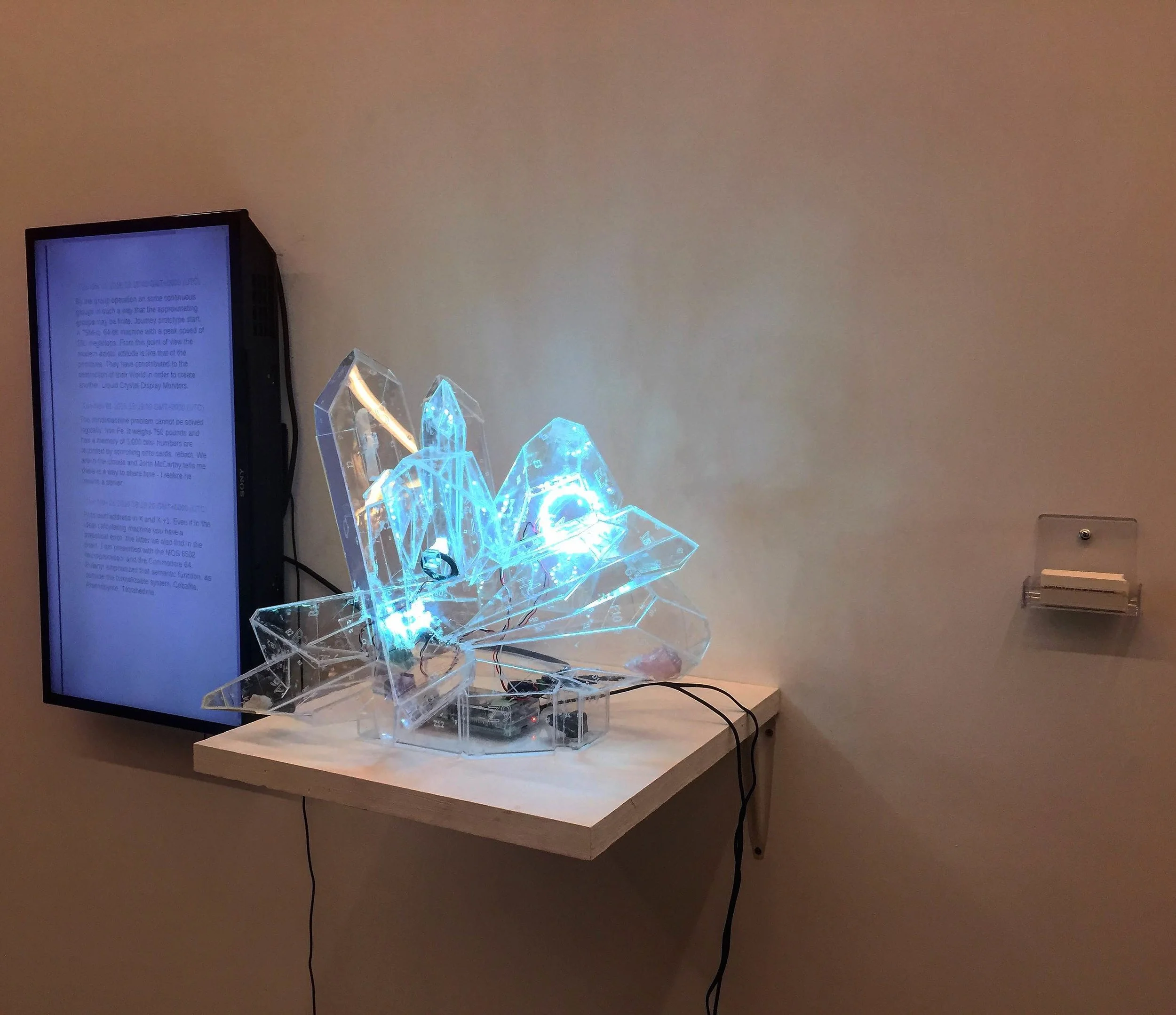 A Computer’s Shamanic Journey (2016 ) Raspberry Pi, Trinket, NeoPixels, Laser Cut Acrylic, Javascript, HTML, CSS, Adruino IDE, Apache, Chrome A Computer’s Shamanic Journey is a proto consideration of how AI could be designed without a human-serving function. The platform for this project begins with a simple Raspberry Pi computer and the idea of shamanic journey. Shamanism is a word that applies to beliefs in many indigenous cultures that everything (including computers) has a spirit and can be communicated with. Interestingly, shaman across the globe use crystals as their main power object for communicating; while in computers, crystals are fundamental parts of a microchip. For healing and learning, shaman journey to the upper and lower worlds. To achieve this, shaman are commonly aided by drumbeats which induce a theta brainwave state (4–7 Hz frequency). In a journey to the upper world, the shaman will likely meet famous spiritual humans in history; have parts of their body ingested, torn off, or burned; and be given knowledge in the form of cryptic verbal teachings. In this work, the Raspberry Pi has opportunities to find similar results. It pulls from six lists housed locally, and compiles a paragraph: famous computers in history, metals that make up the Pi’s components, human “spirit ancestors” of computers, historical conversations regarding the sentient power of computers, shamanic references, and famous code. What is knowable to the computer regarding itself remains unclear but references to different mathematical hypothesis of this problem are included, and become possible results. https://withquietintentions.github.io/