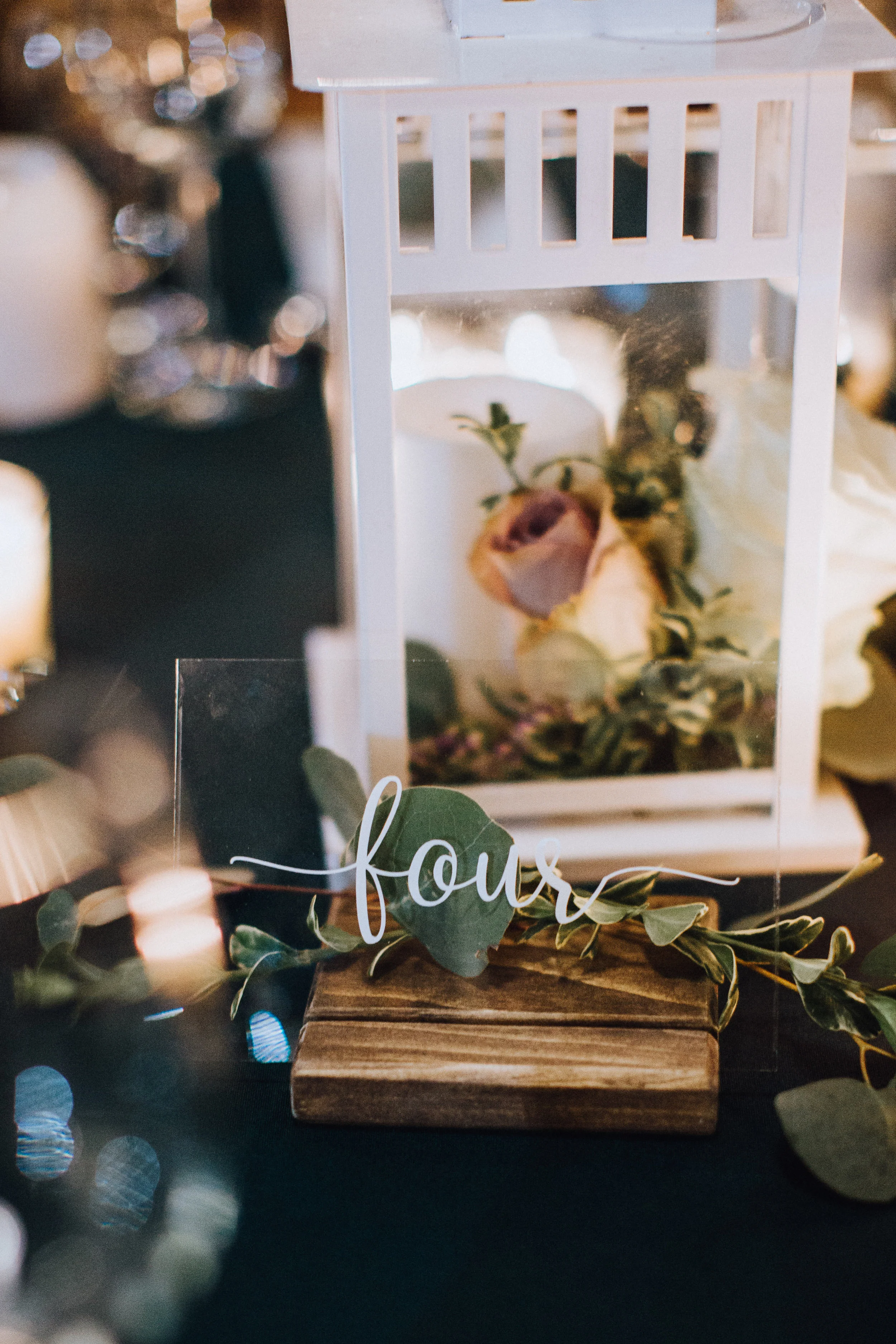 Glass script table numbers with wooden base White lanterns (flowers not included) Photo by Jenna Rachelle Photography
