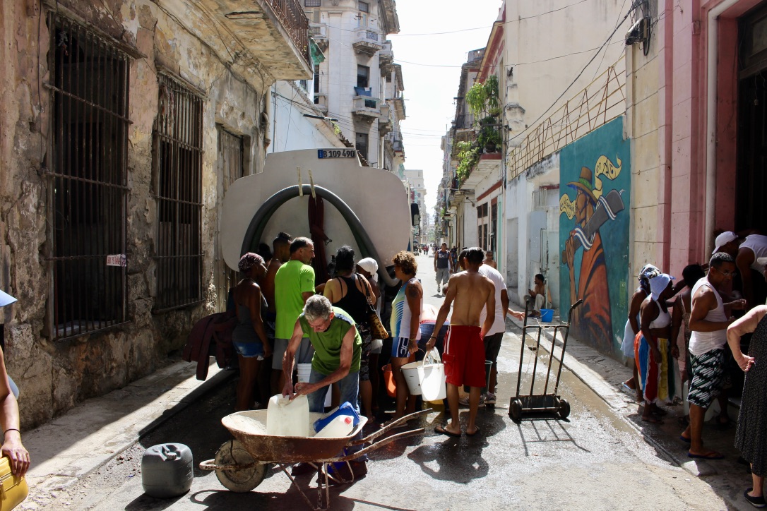 Locals collecting water rations outside of El Cafe in Havana 