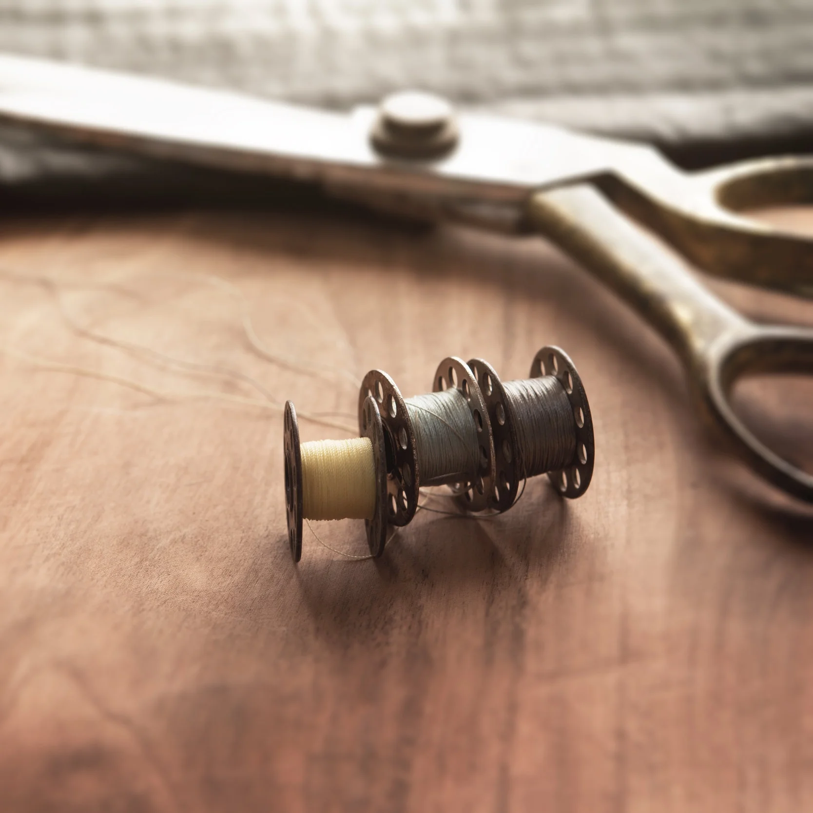 stock-photo-old-sewing-machine-bobbins-with-gold-brass-scissors-and-black-silky-fabric-on-a-old-grungy-work-243941014.jpg