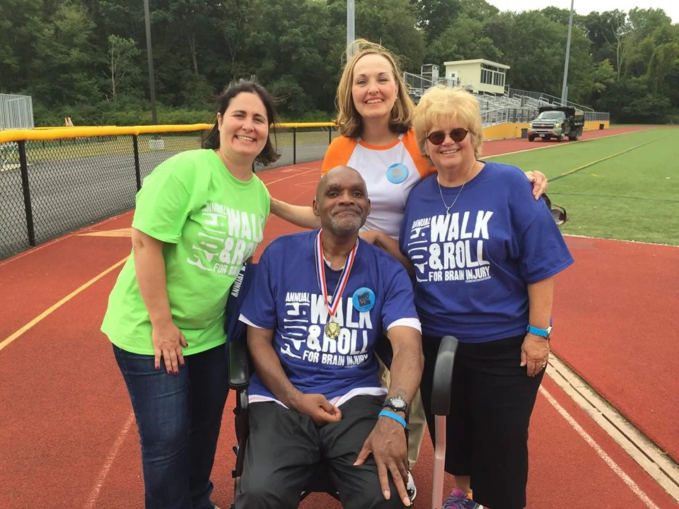 CRC staff congratulate a client for finishing a lap of the track at the Brain Injury Association of Massachusetts Walk & Roll