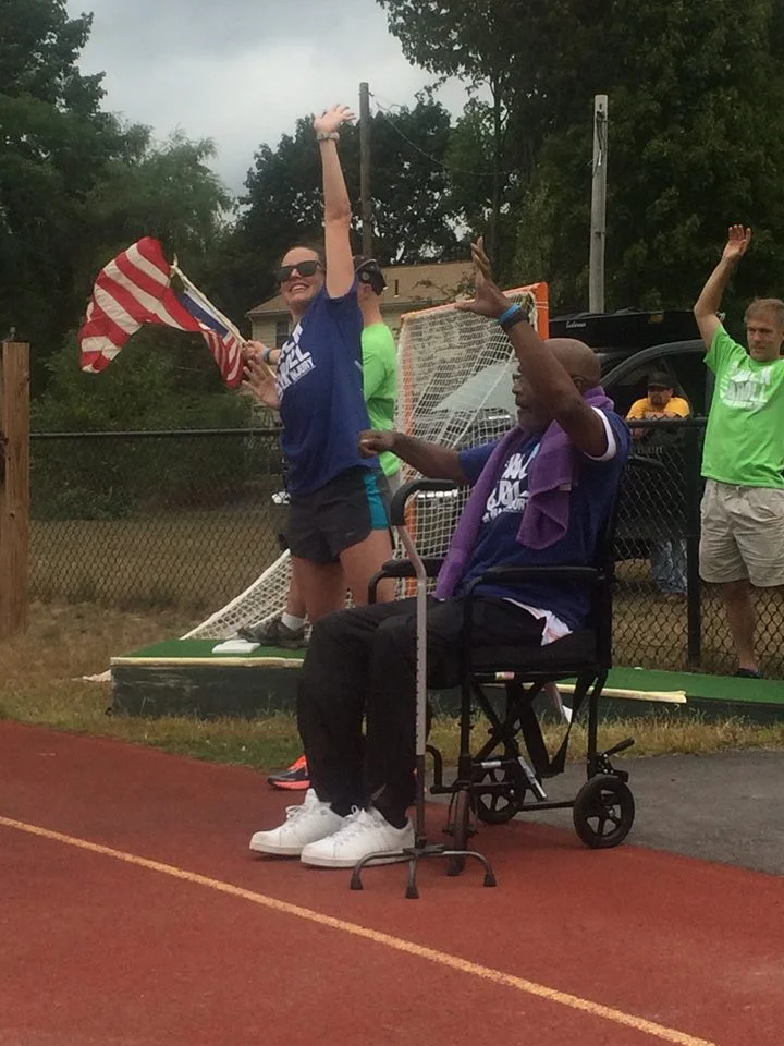 A Community Rehab Care client completes his goal of walking a lap of the track at the BIA-MA Walk & Roll