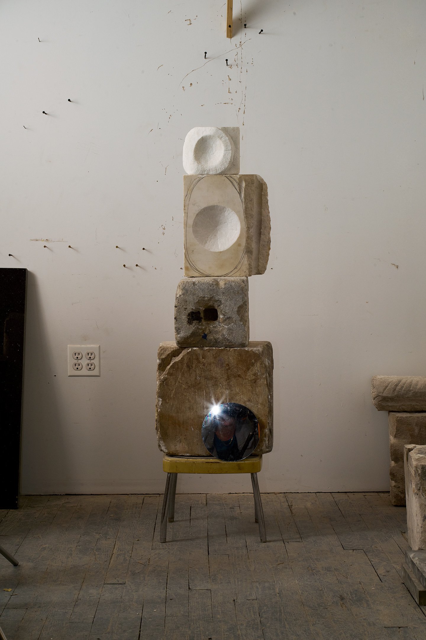  Photograph of:  Voids I , 2023-24, Marble, granite, wood, stool, 45” X 12” X 10”  Photograph (with mirror and lights) by Hannah Whitaker for "Dim, Dahlia, Violet, Stone" (ITI Press, 2024) 