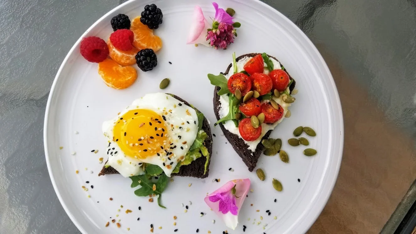 A guest favorite ~ gourmet avocado toast with arugula, fried egg and goat cheese coupled with ricotta on pumpernickel, roasted tomatoes and pumpkin seeds.