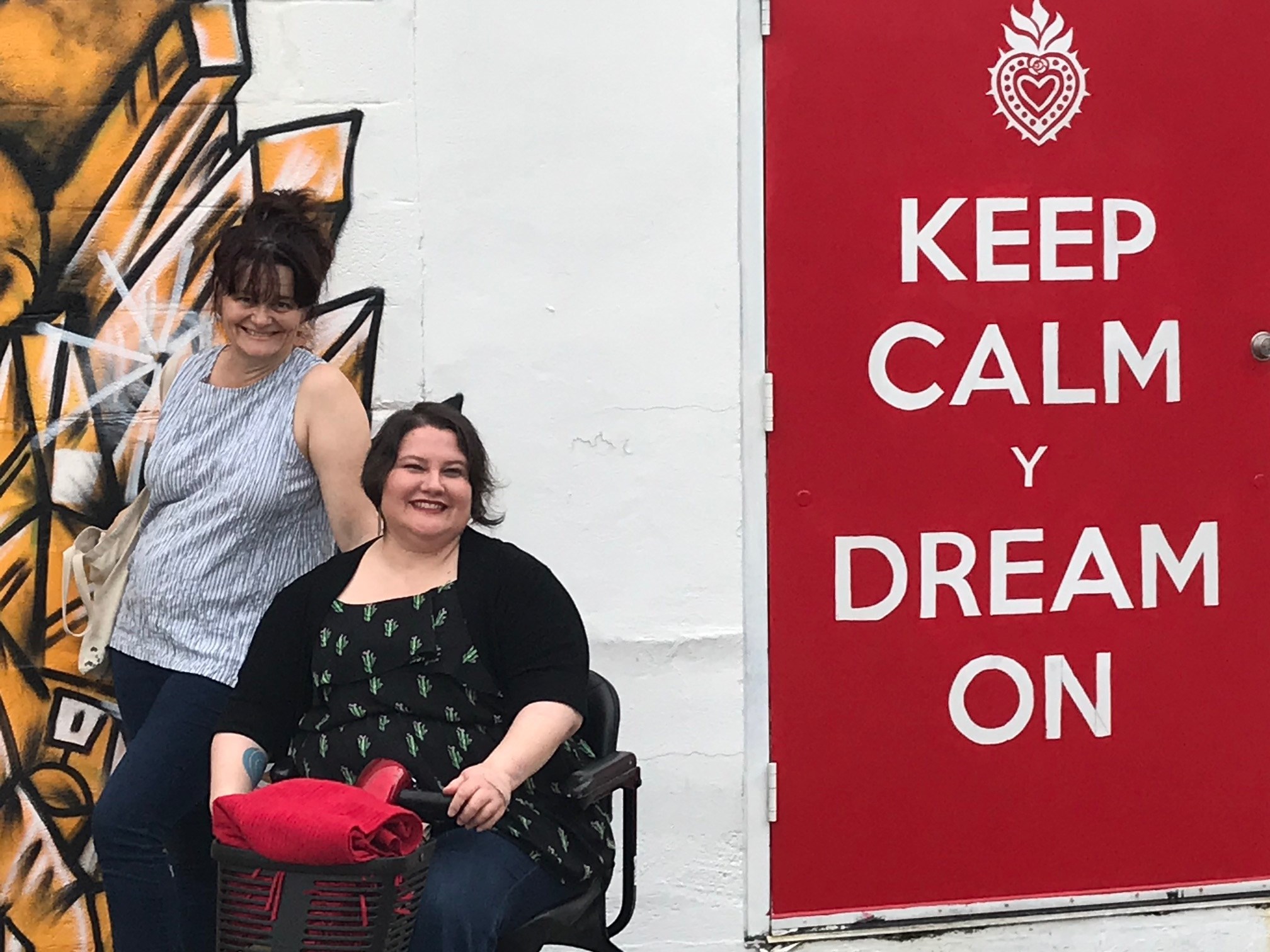                      Founder Connie Voisine poses with 2019 Conference participant beside a “Keep Calm Y Dream On” banner. 
