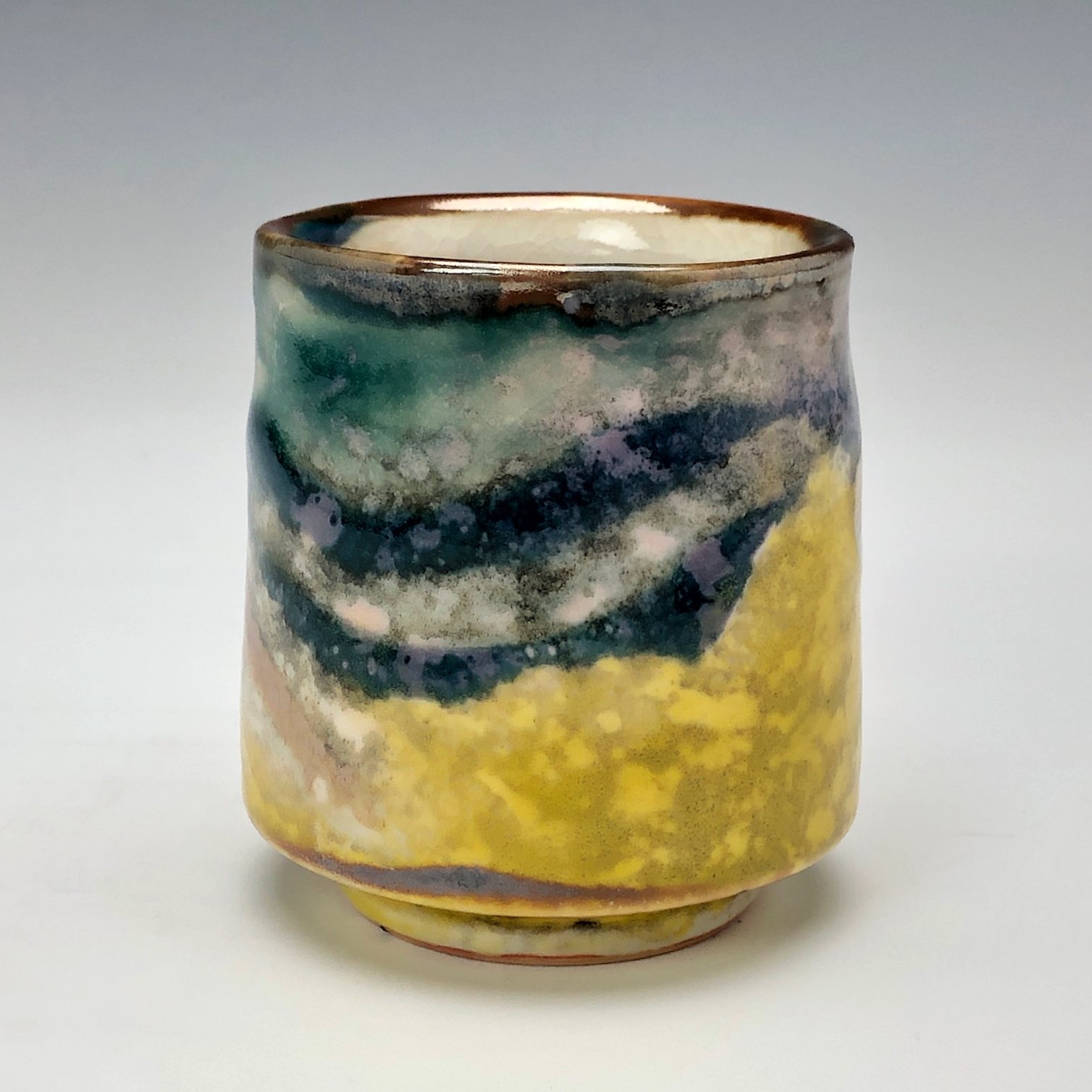  Bruce Gholson, Bulldog Pottery, Seagrove, North Carolina   Yunomi 2  - Casual drinking cup made from porcelain with Iron Luster Fish. Ceramic cup also has swipes of yellow and blue. A textural shino is also glazed onto the some areas of the cup’s su