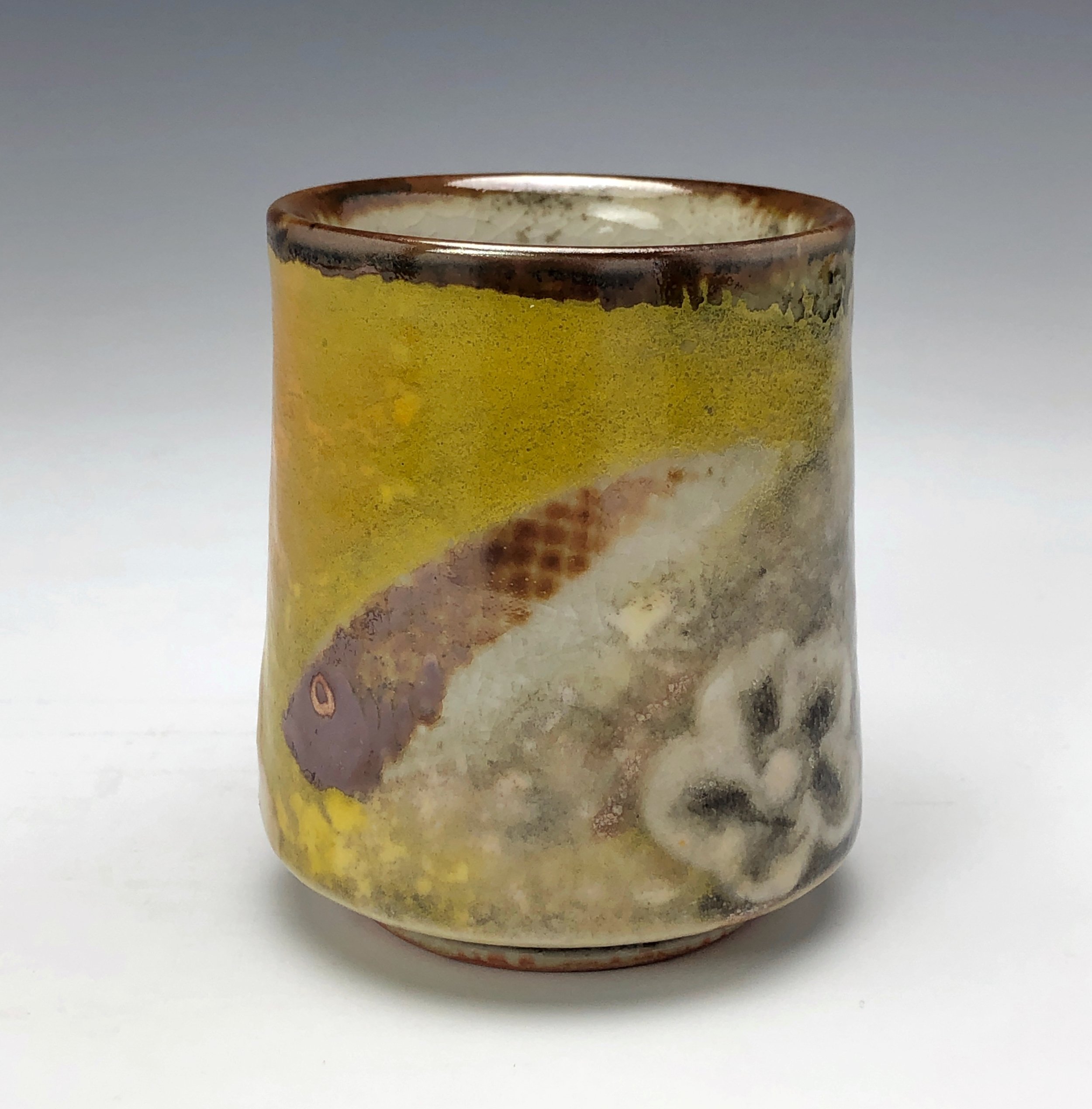  Bruce Gholson, Bulldog Pottery, Seagrove, North Carolina   Yunomi 3 - Casual drinking cup made from porcelain with Iron Luster Fish. Ceramic cup also has swipes of yellow and blue with a cobalt blue transfer. A textural shino is also glazed onto the