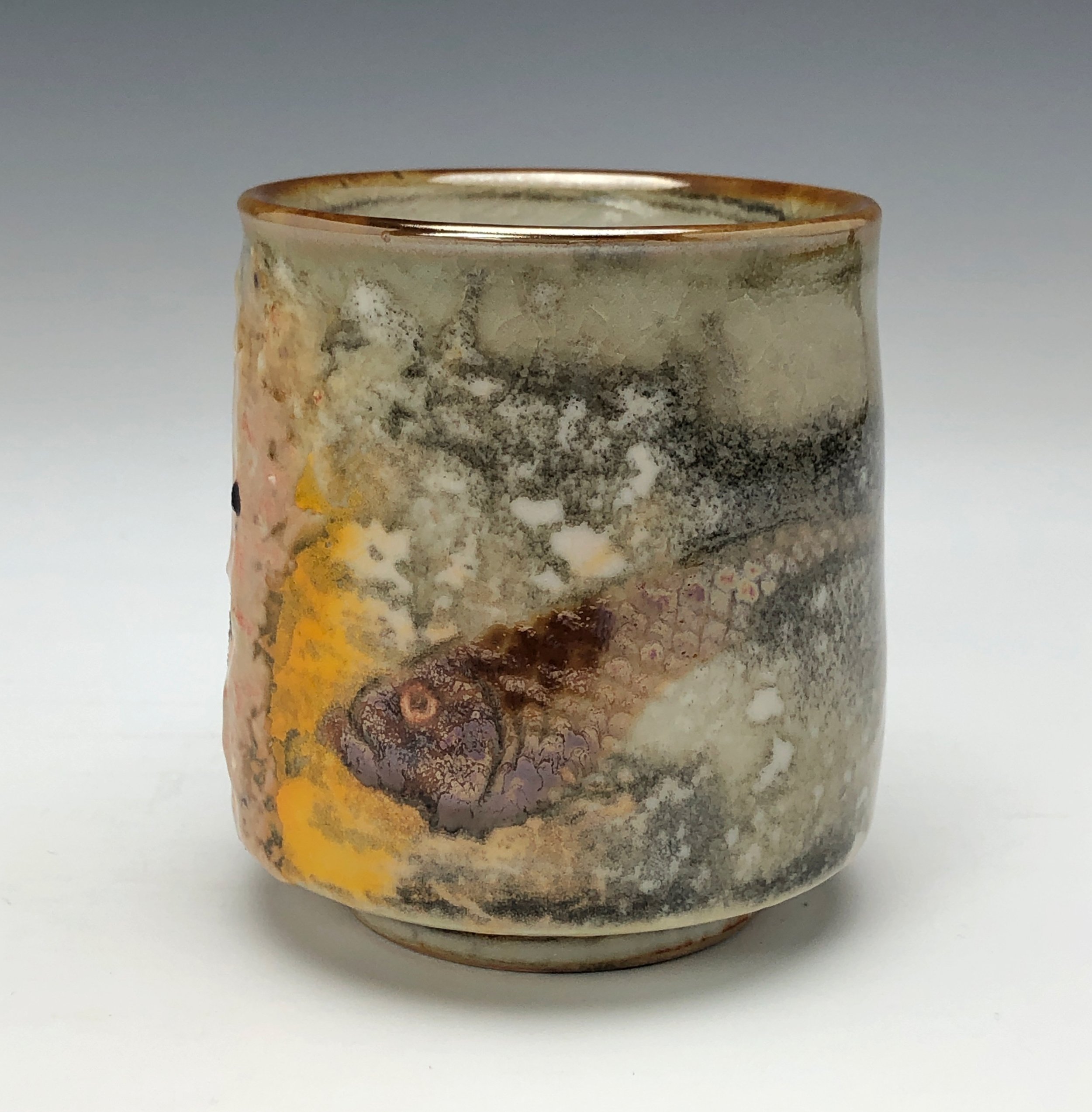  Bruce Gholson, Bulldog Pottery, Seagrove, North Carolina   Yunomi 5  - Casual drinking cup made from porcelain with Iron Luster Fish. Ceramic cup also has swipes of yellow and blue. A textural shino is also glazed onto the some areas of the cup’s su