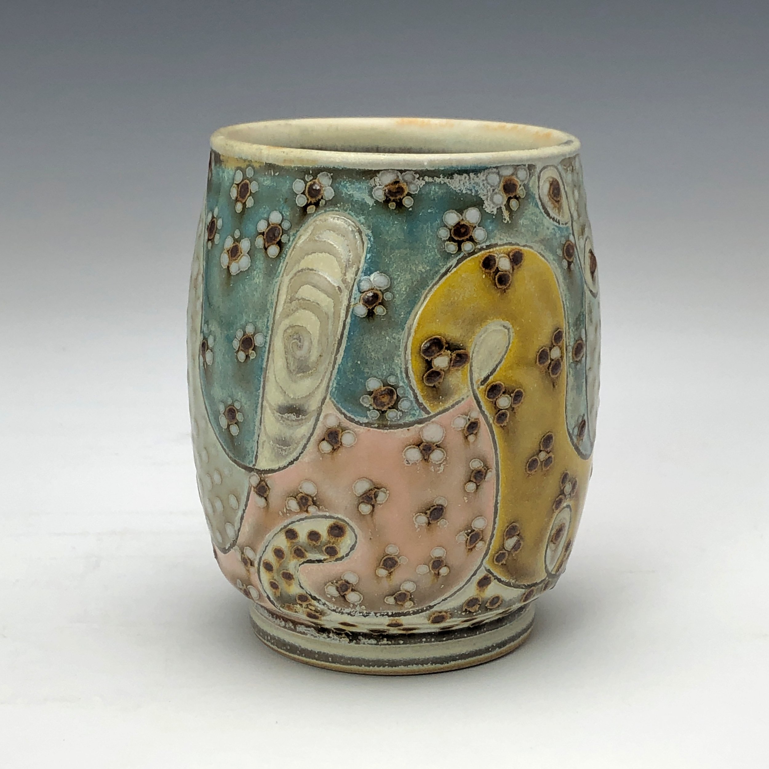  Samantha Henneke, Bulldog Pottery, Seagrove, North Carolina  Yunomi 2- Casual drinking cup made from a smooth white porcelaneous clay body. Pattern Medley patterns are made with slip and glaze dot patterns. Translucent vellum glaze over various unde