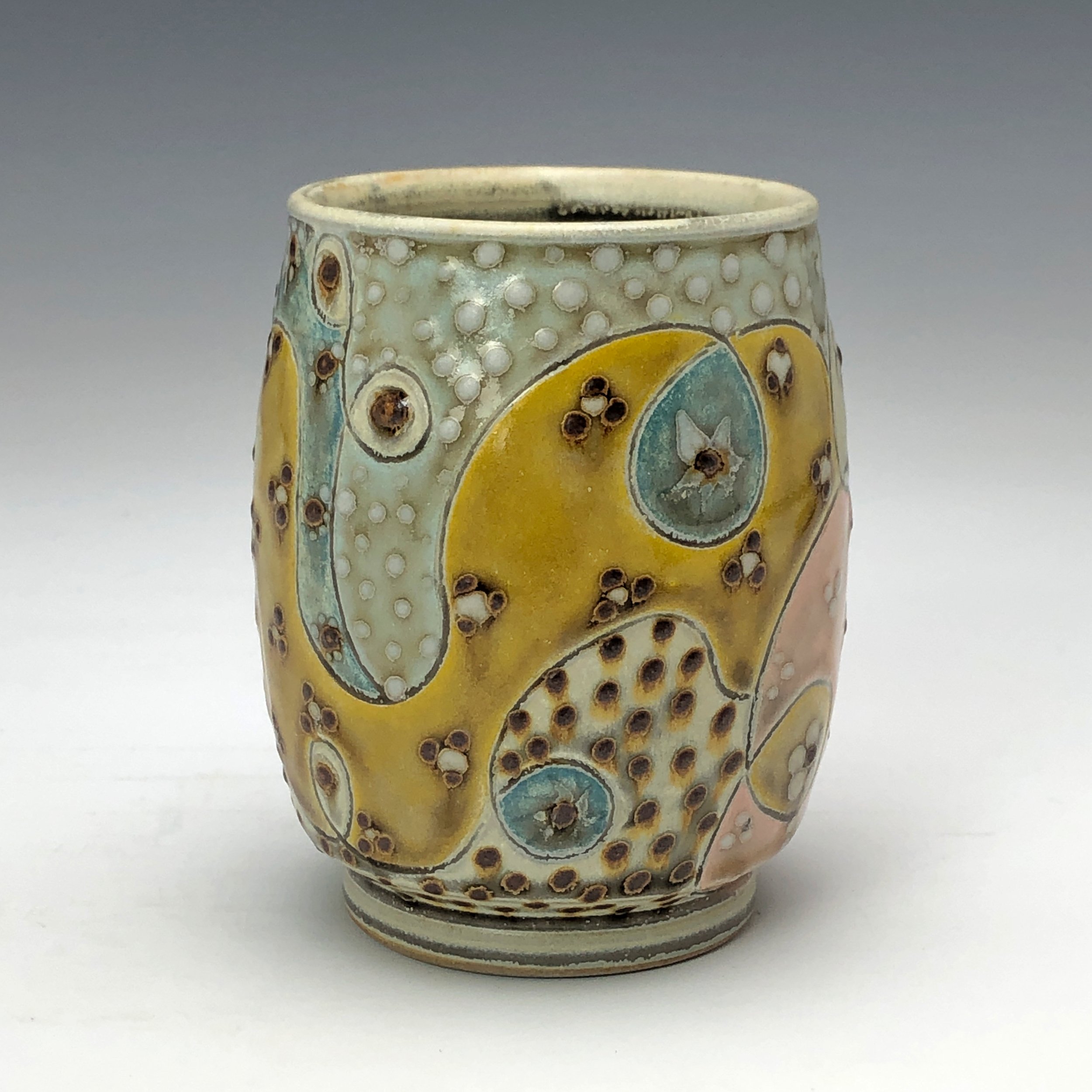  Samantha Henneke, Bulldog Pottery, Seagrove, North Carolina  Yunomi 2- Casual drinking cup made from a smooth white porcelaneous clay body. Pattern Medley patterns are made with slip and glaze dot patterns. Translucent vellum glaze over various unde
