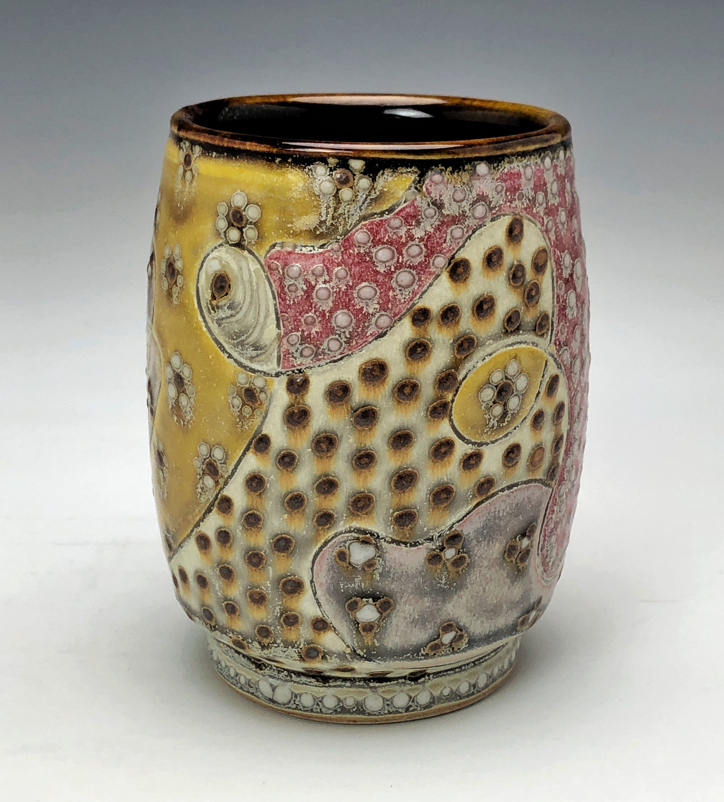  Samantha Henneke, Bulldog Pottery, Seagrove, North Carolina  Yunomi 3- Casual drinking cup made from a smooth white porcelaneous clay body. Pattern Medley patterns are made with slip and glaze dot patterns. Translucent vellum glaze over various unde