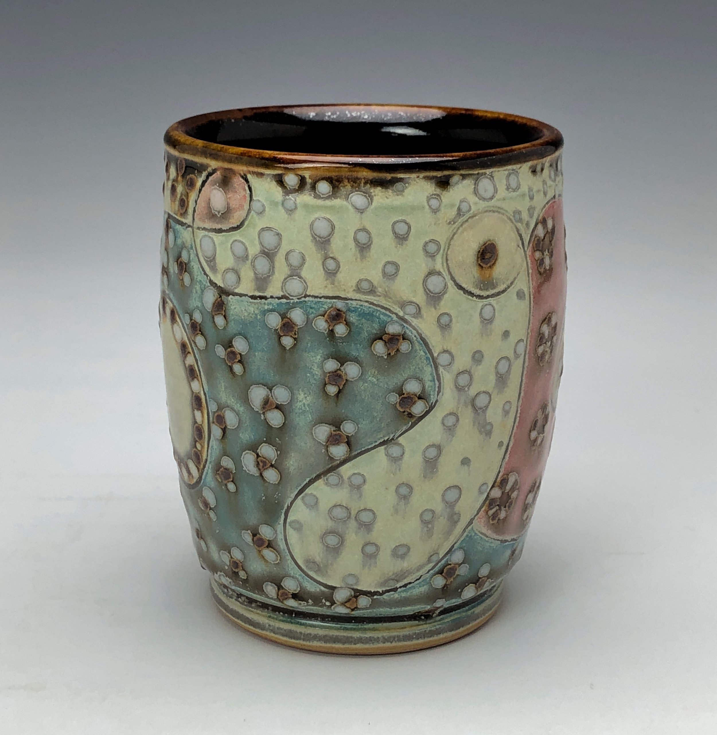  Samantha Henneke, Bulldog Pottery, Seagrove, North Carolina  Yunomi 5- Casual drinking cup made from a smooth white porcelaneous clay body. Pattern Medley patterns are made with slip and glaze dot patterns. Translucent vellum glaze over various unde