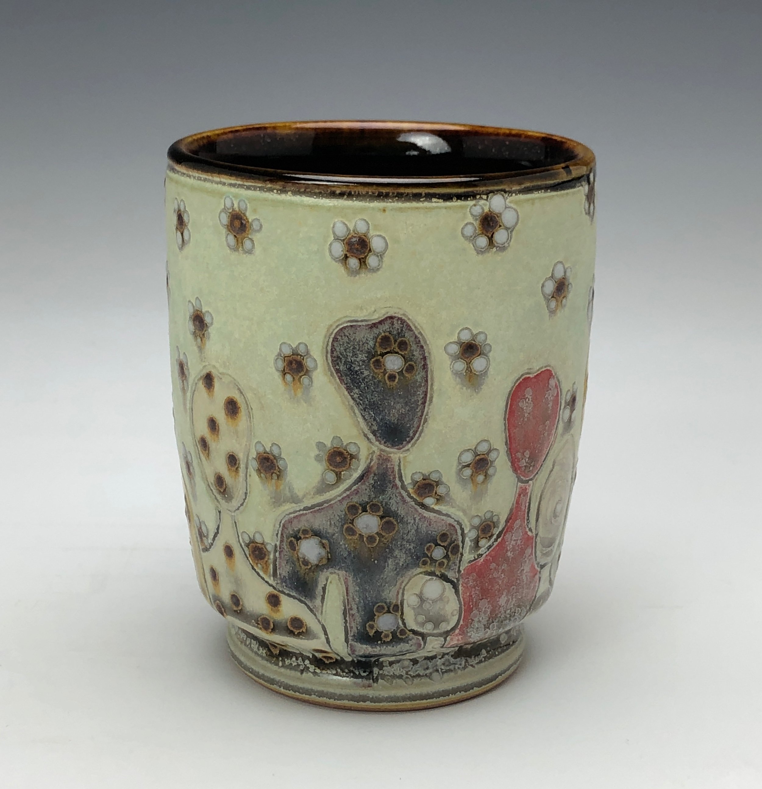  Samantha Henneke, Bulldog Pottery, Seagrove, North Carolina  Yunomi 6- Casual drinking cup made from a smooth white porcelaneous clay body. Figurative decoration with slip and glaze dot patterns. Translucent vellum glaze over various underglaze colo