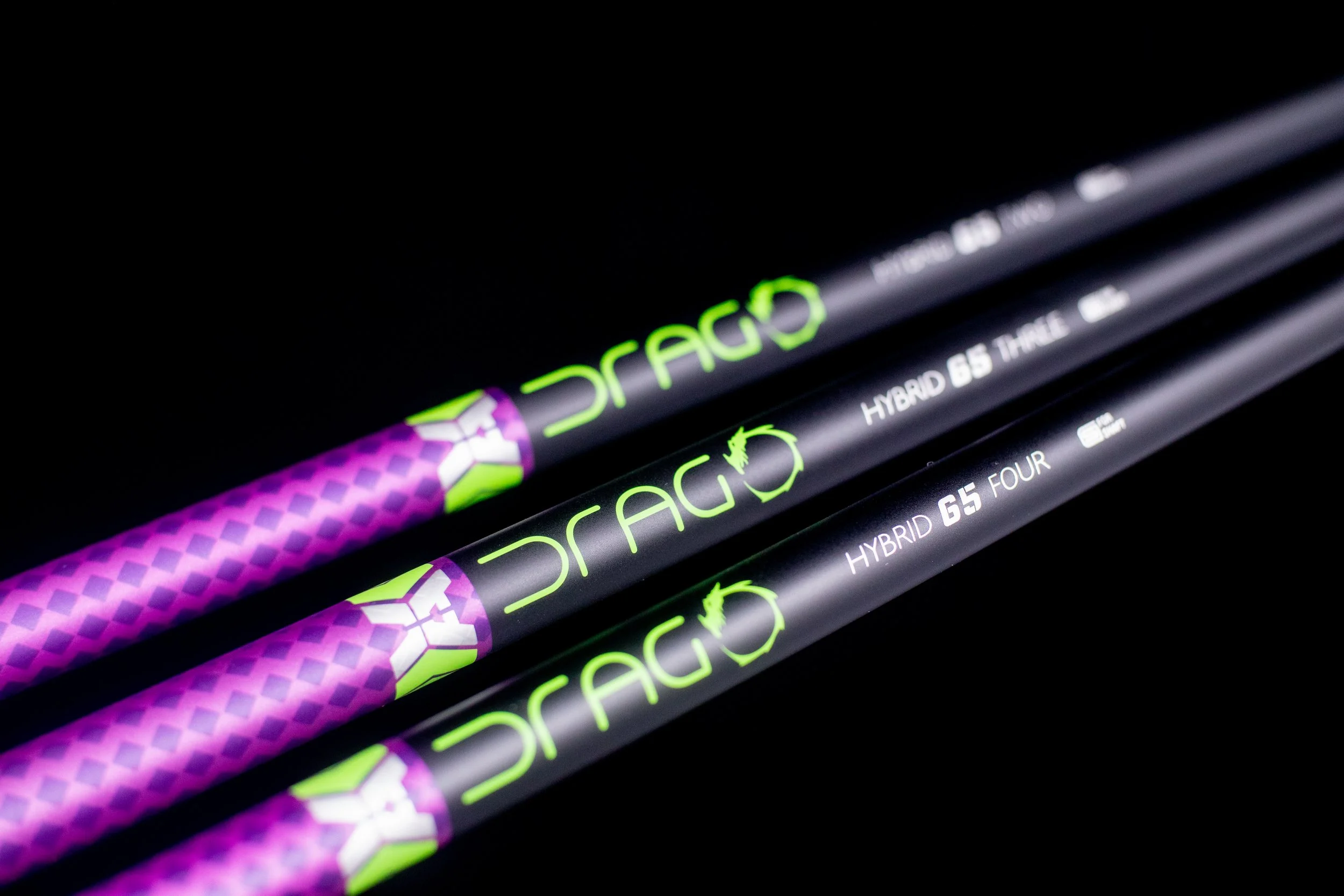 Three black golf clubs with green and purple accents and the words 'DRAGO', 'HYBRID G5 FOUR', and 'HYBRID G5 THE' written on them, arranged diagonally against a black background.