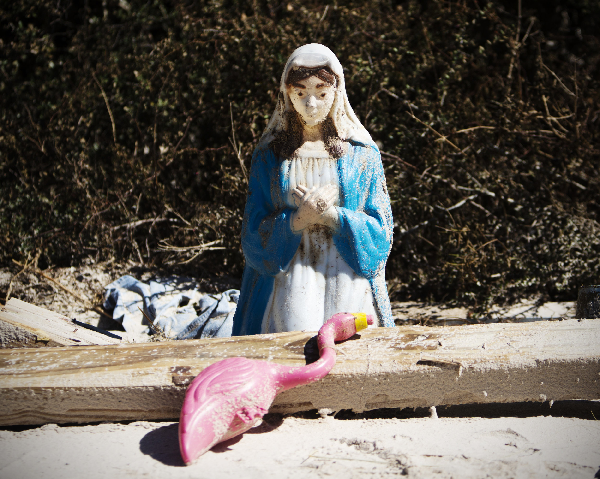 A Virgin Mary sits over a plastic flamingo near debris on Alligator Drive in Alligator Point on October 12, 2018.