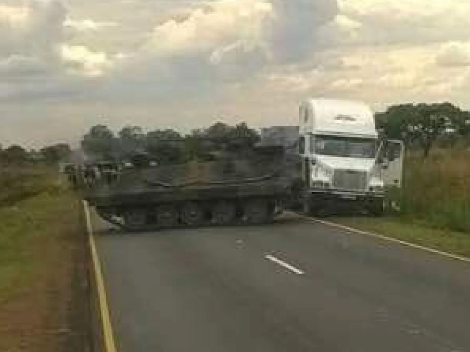 An armoured personnel carrier manoeuvres along the road between Norton and Harare