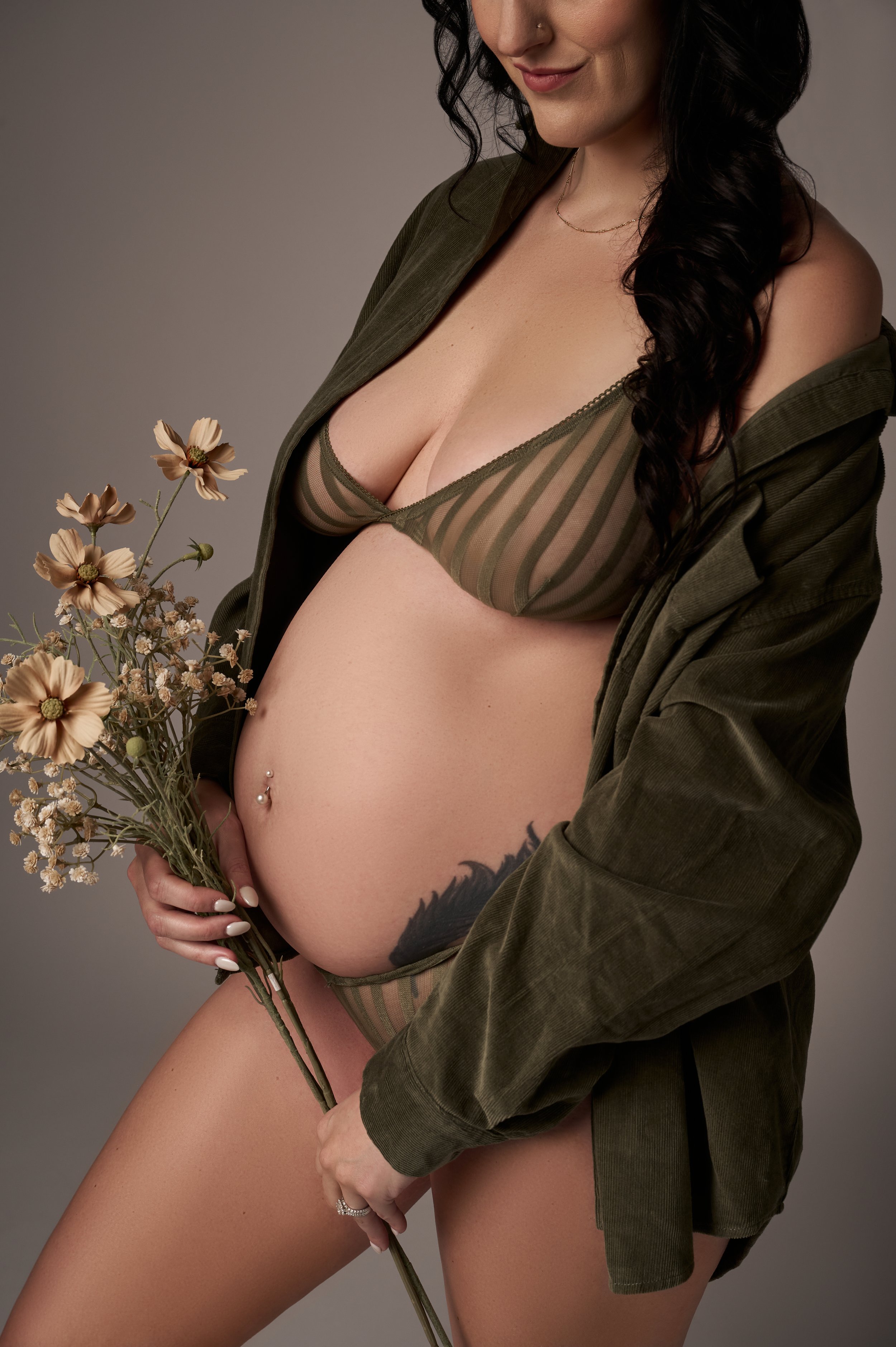 pregnant woman holding flowers in green lingerie.jpg