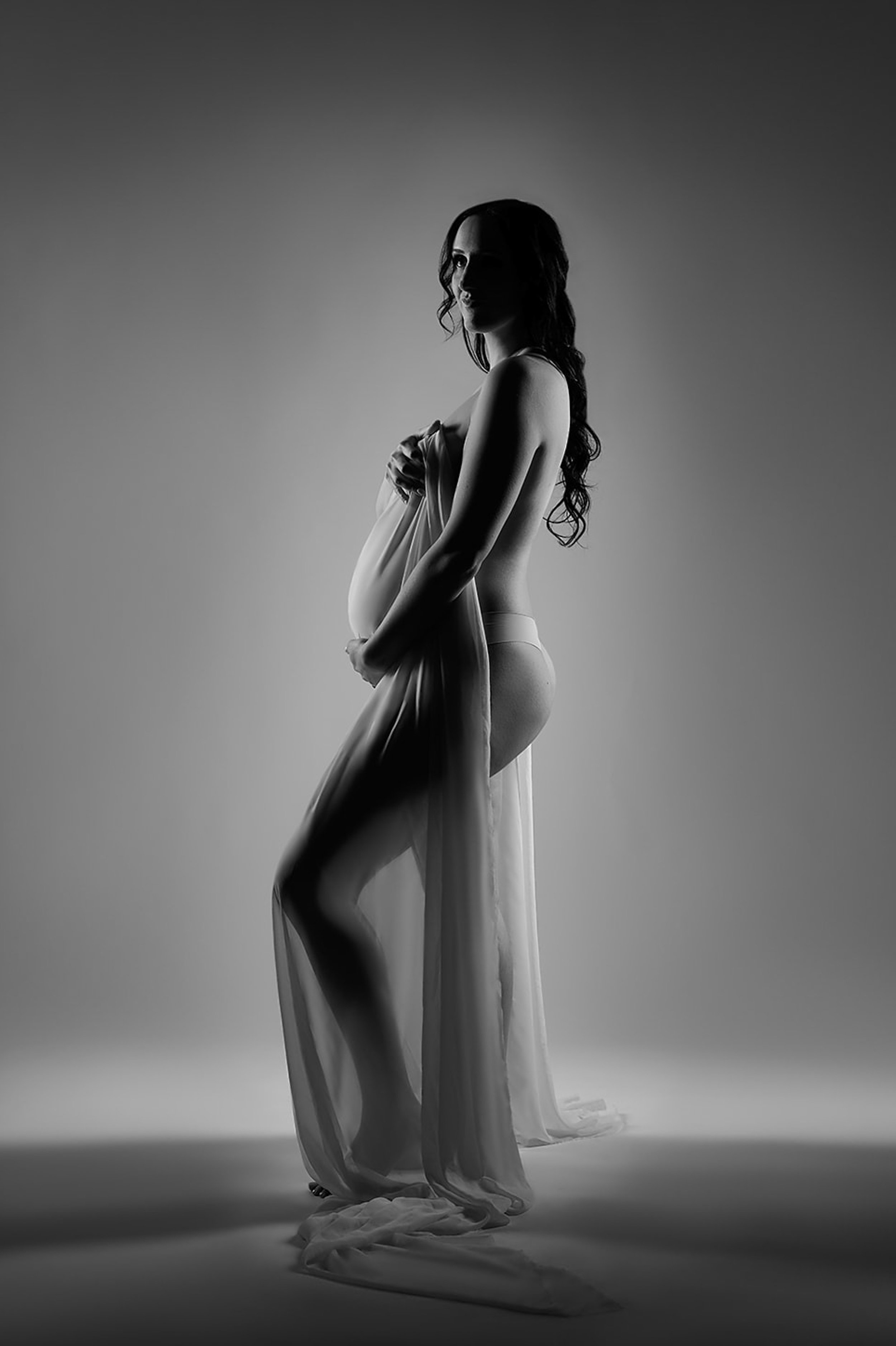  A silhouette of a pregnant woman holding her bump. 