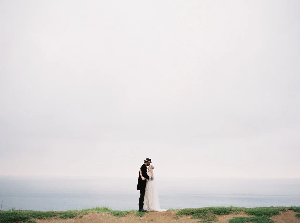 Danyale and Matthew Photography by Erich McVey . The wedding of Danyale, in SHAREEN Bridal (the “ Karine ” with sleeves), and husband Matthew. Flowers by Burst & Bloom . Venue is Wind & Sea Estate in Big Sur, CA.