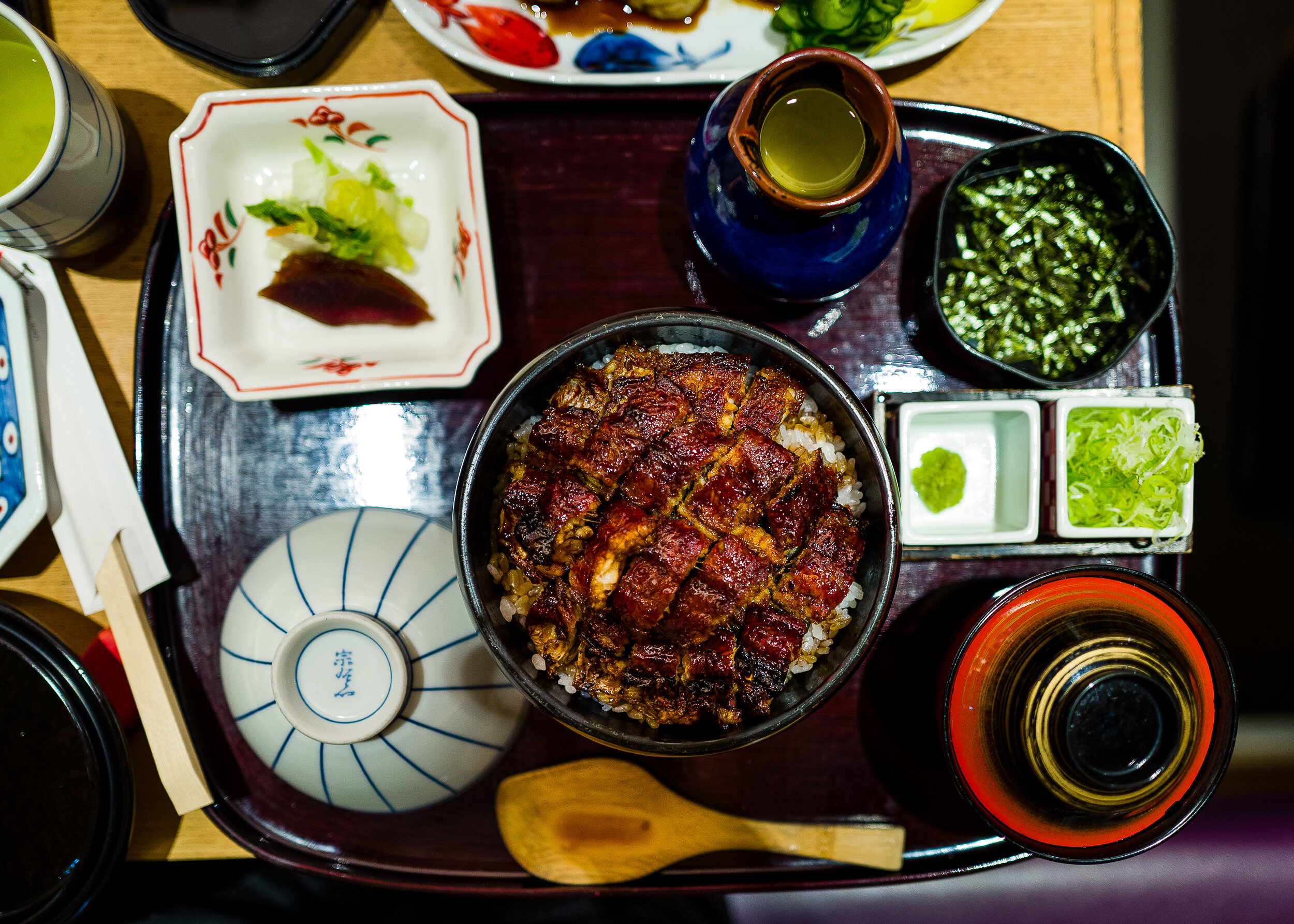  Clockwise from upper left corner: tsukemono (pickles), green tea, nori flakes, scallion and wasabi, miso soup, serving spatula, eating bowl, unagi and rice 