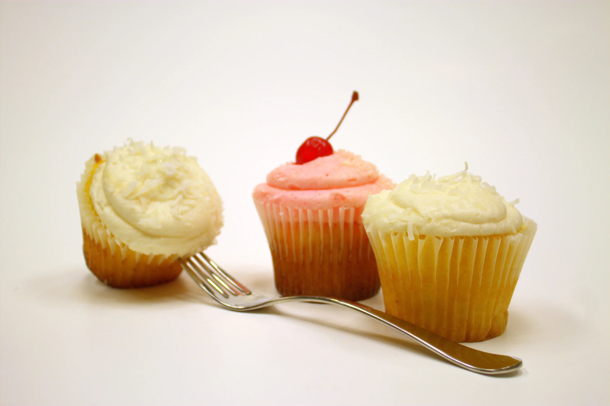 Cupcakin’ Bakery - Pineapple Cupcake with buttercream icing and coconut shavings; Strawberry Delight Cupcake topped with strawberry buttercream icing, pearls and a cherry; $3-$3.75 each