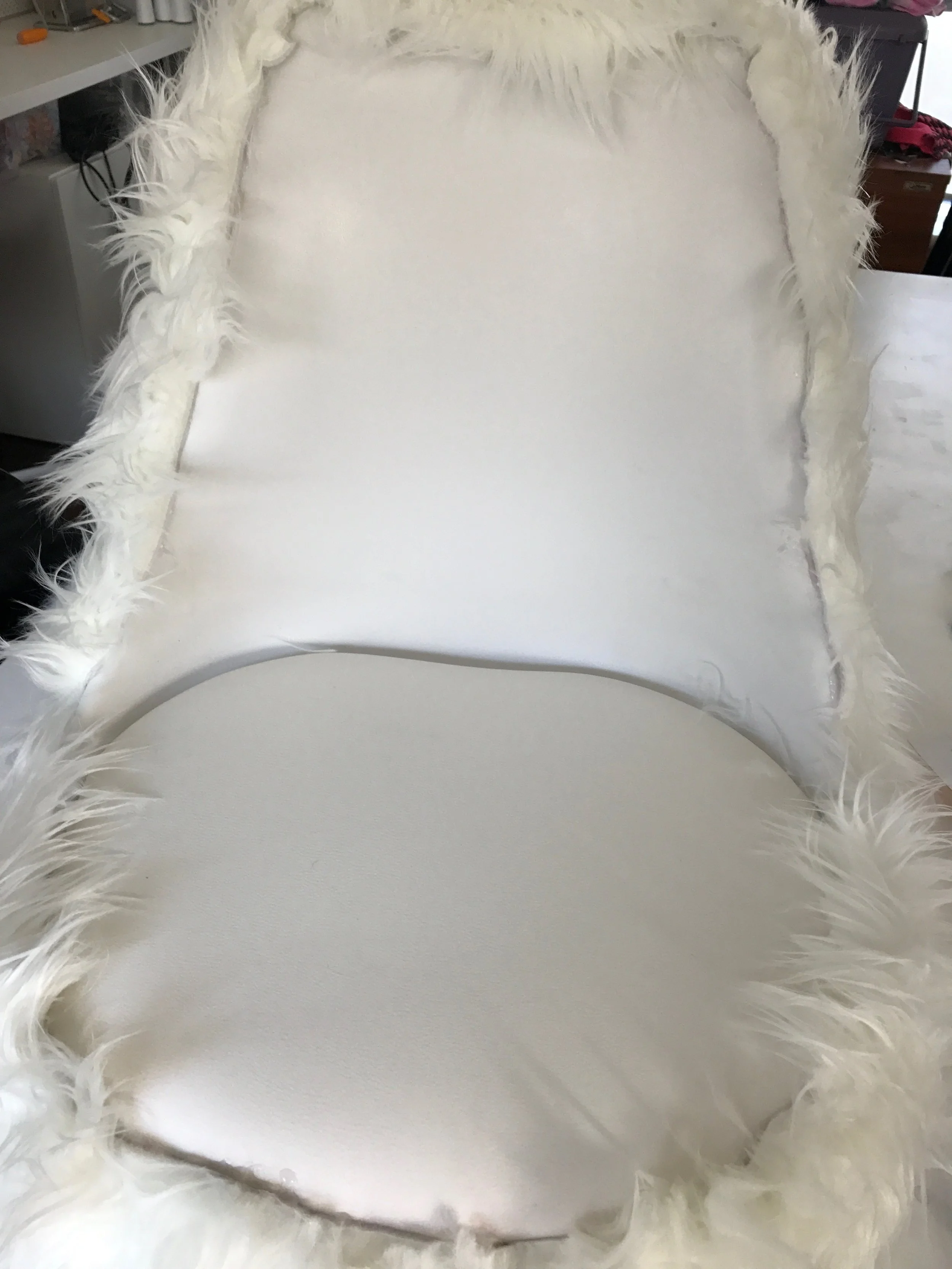 Using a hot glue gun, glue the cut rug to the back of the chair, wrapping under and securing around the circle. Be sure to wrap the sides over too, as pictured.