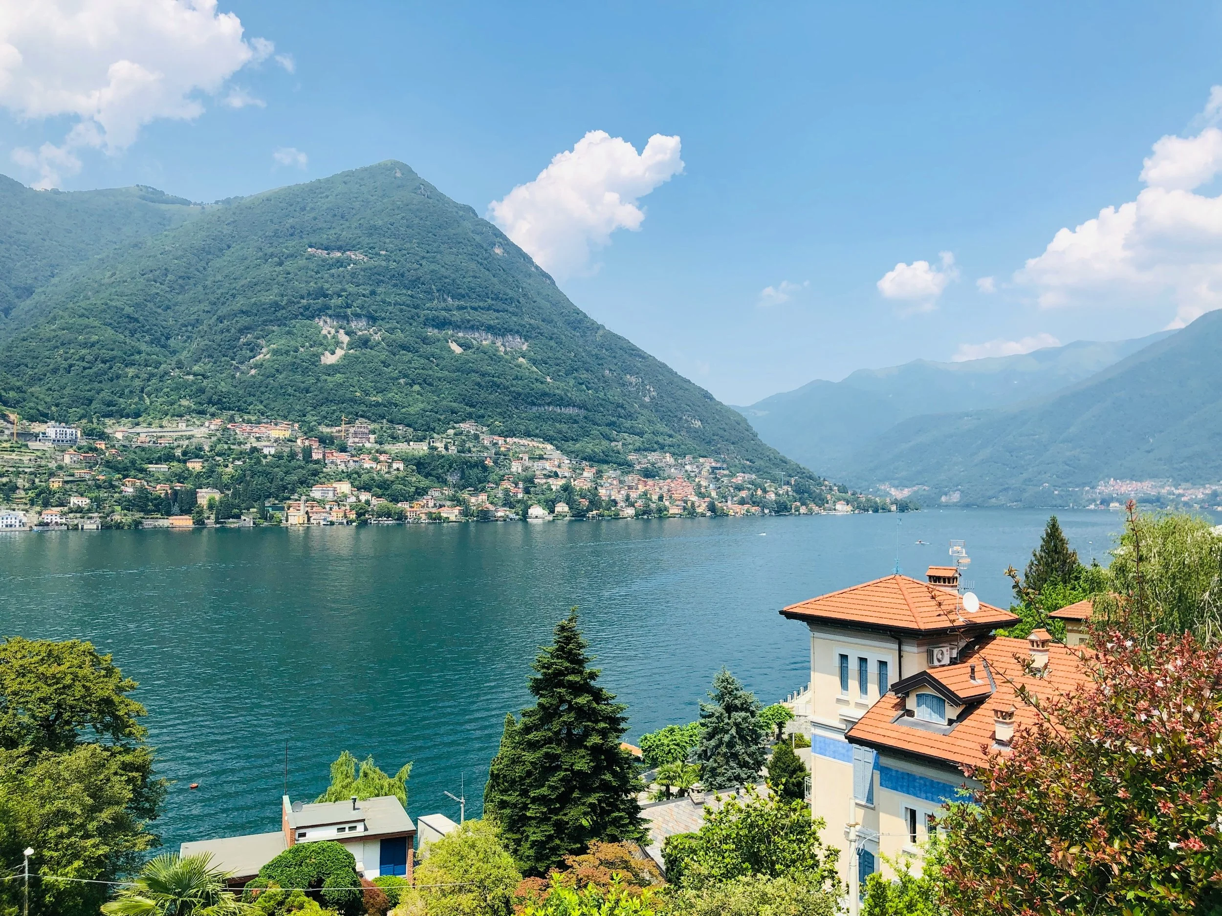A lake in Lombardy with hills and villas In the distance.