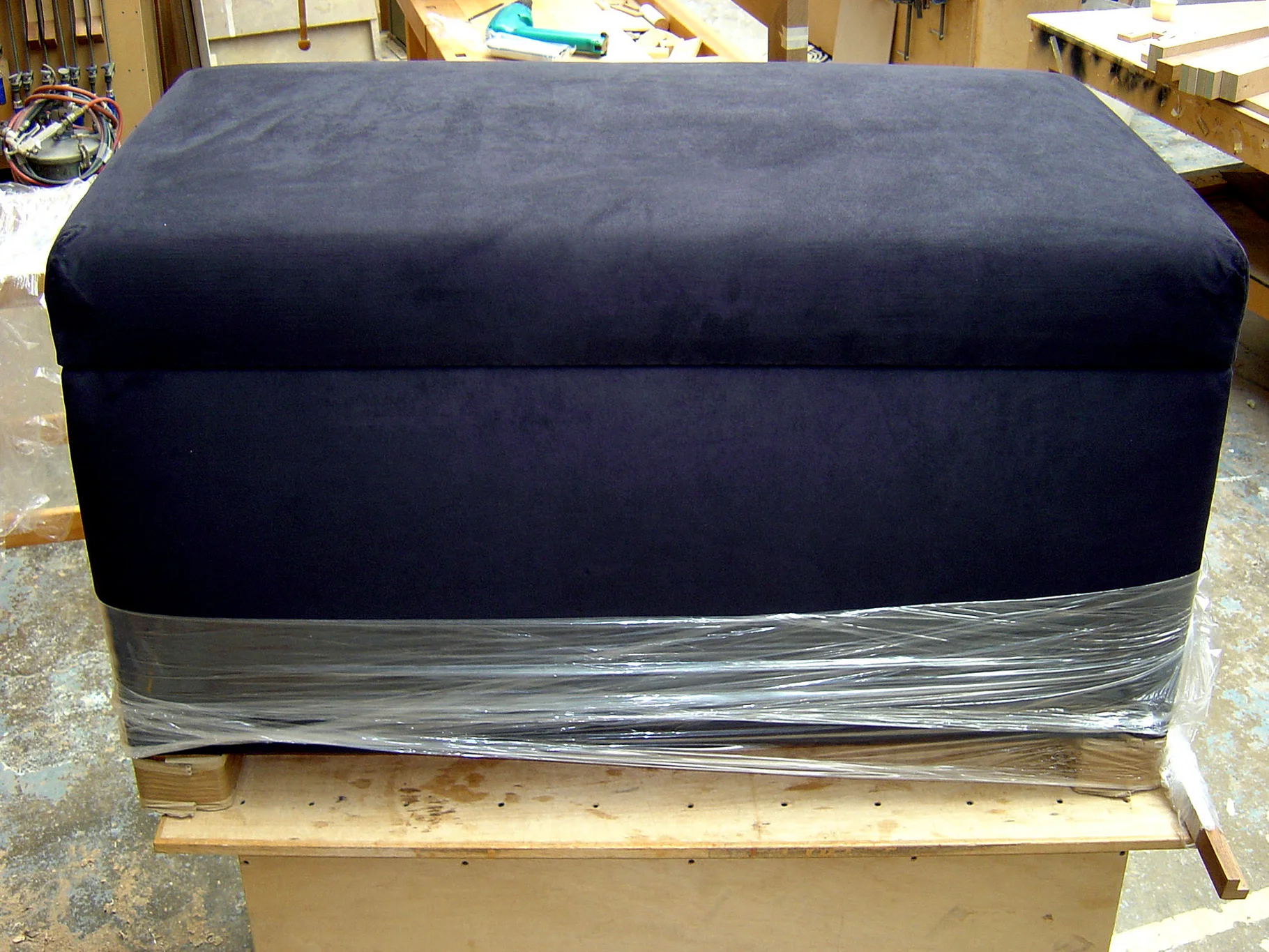 End of bed ottoman chest upholstered in dark blue suede with concealed automated TV lift in lid