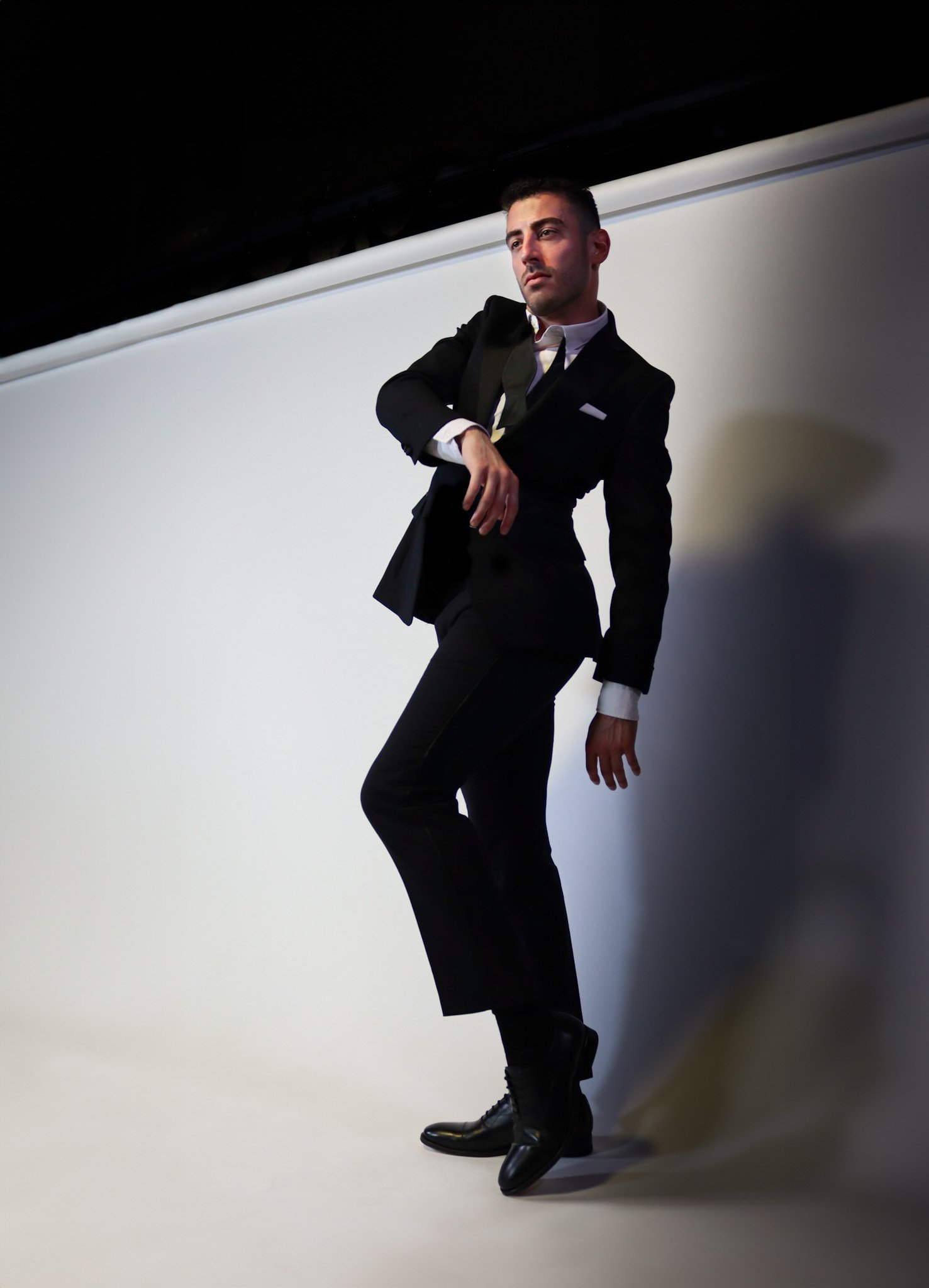 Man in a black tuxedo posing against a white backdrop.