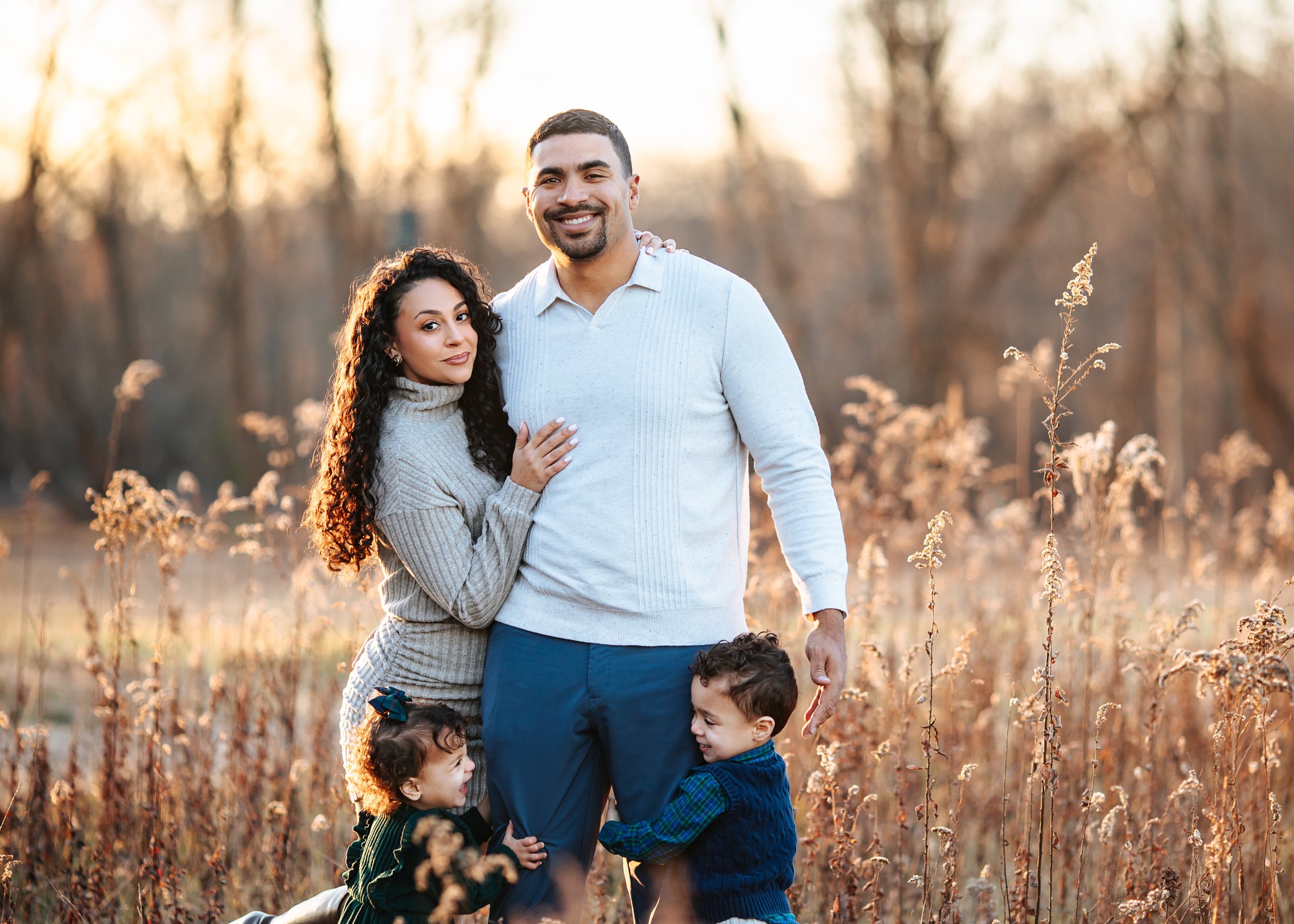Latino Family looking at the camera with a beautiful sunset behind them during the fall in a Boonton, Nj Location