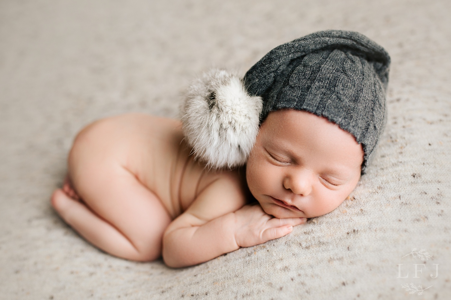 baby boy with gray pom pom hat posed tushy up