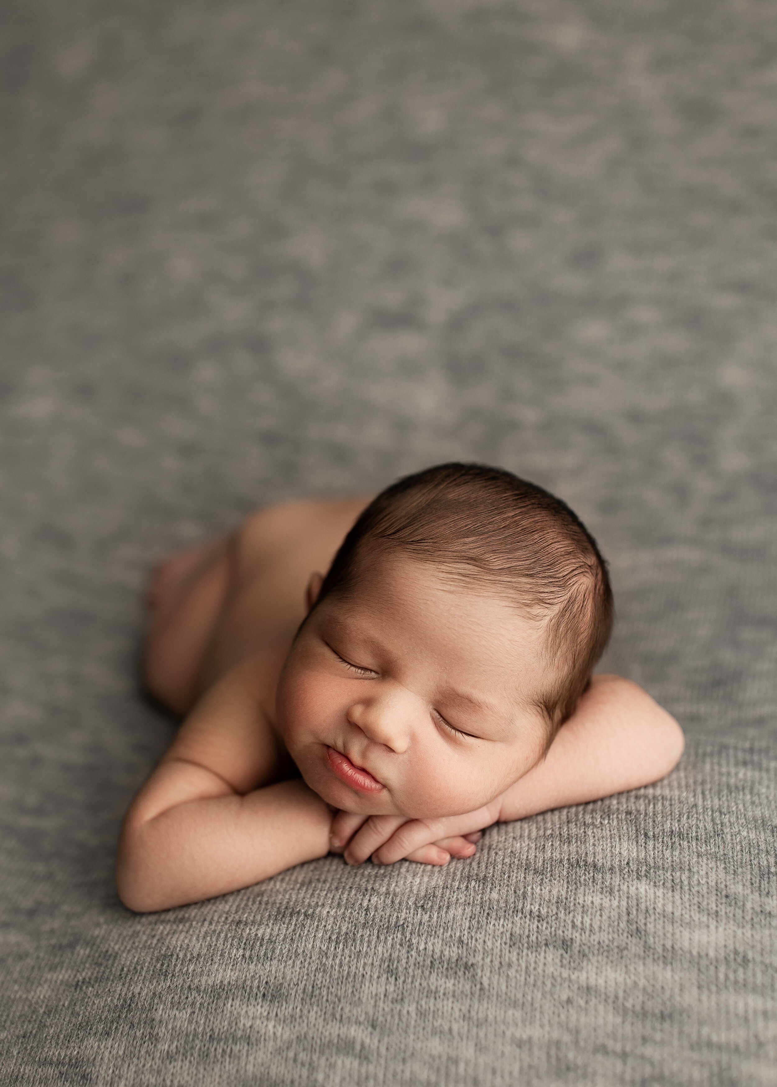 Sleeping newborn baby on gray blanket. Sleeping during his newborn session with Tamara Vaz Photography.