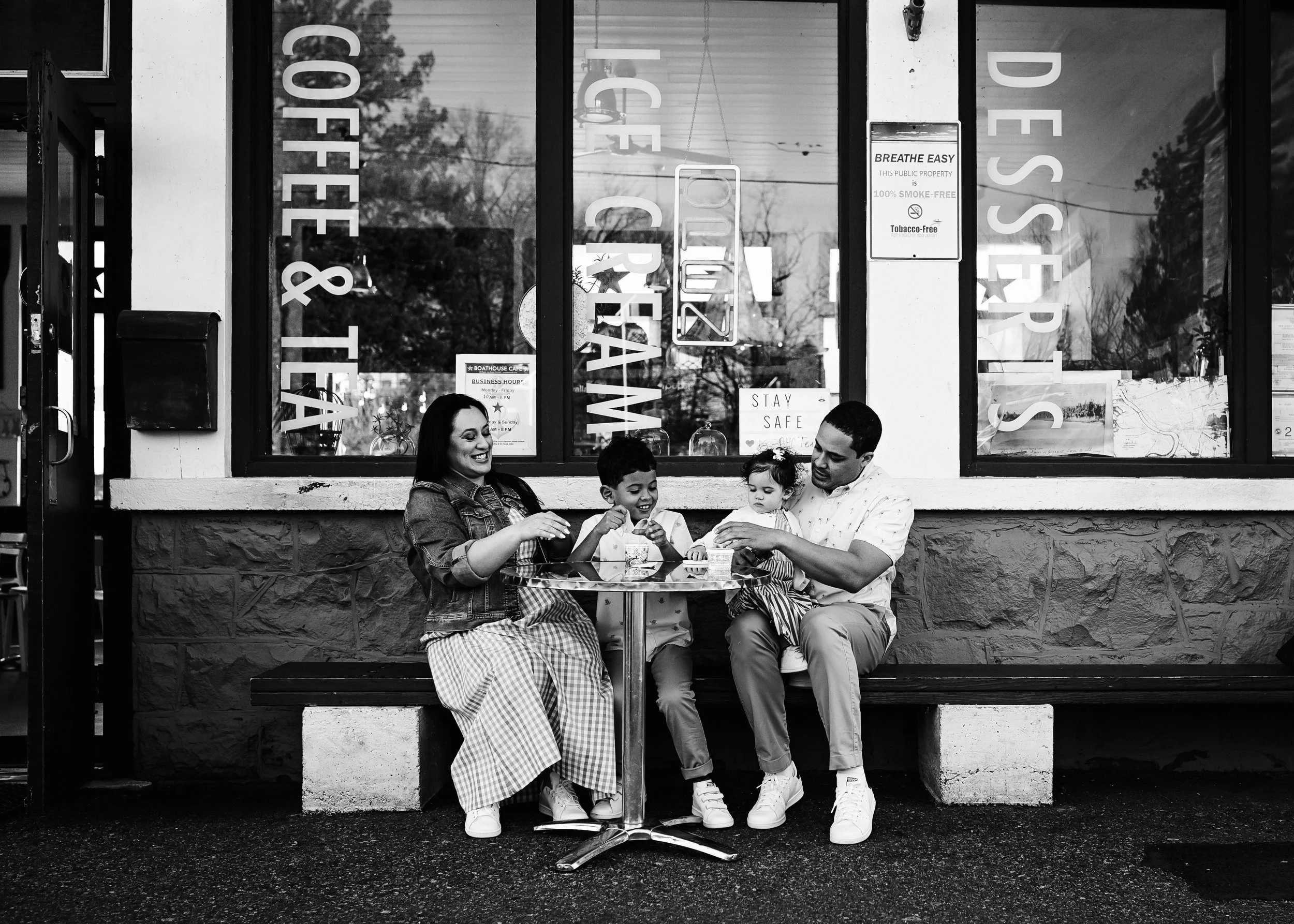 Black and white image of family eating ice cream looking happy and having fun. Dad is helping his baby girl