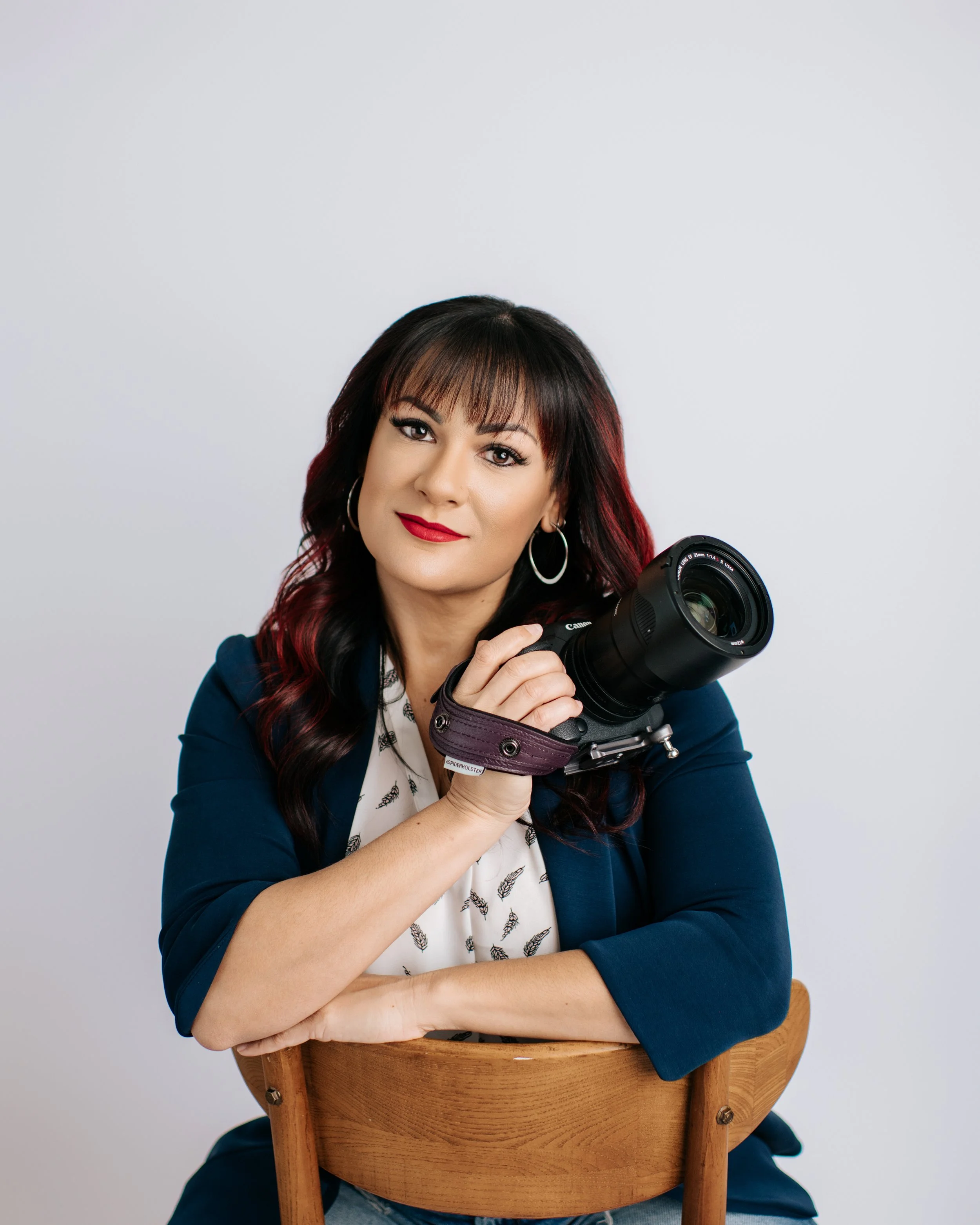 Tamara Gavish seated holding a camera posing for her headshot