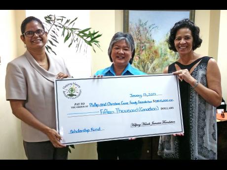 Karen McDonald-Gayle (left) of the Helping Hands charity organisation hands over a cheque to Dr Susan Chang-Lopez (centre), of the Reach Up and Learn Programme and head of the Epidemiology Research Unit at the University of the West Indies (UWI), and Christine Gore, director, Gore Family Foundation.