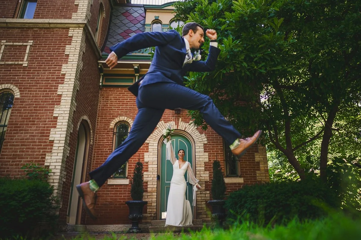 groom in foreground appearing to jump over bride in background. Bride has comical excited expression
