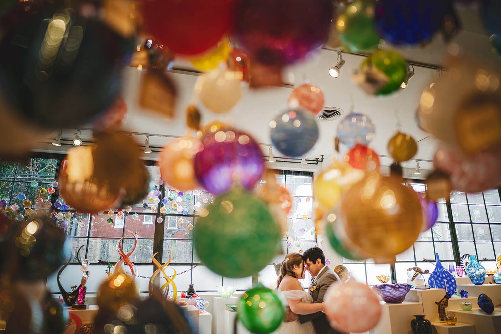 couple standings facing each other in an intimate moment surrounded by glass sculptures in the foreground at Third Degree Glass wedding venue in St Louis