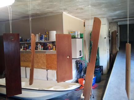 Main bench seat with first coat. Other wood hanging from small hooks about to get varnished.