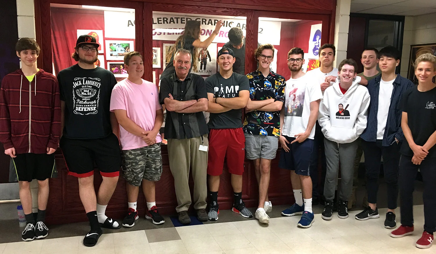 Mr. Inlander (Don) and his Accelerated Graphic Arts II students. Two students are in the glass case behind him, installing artwork.