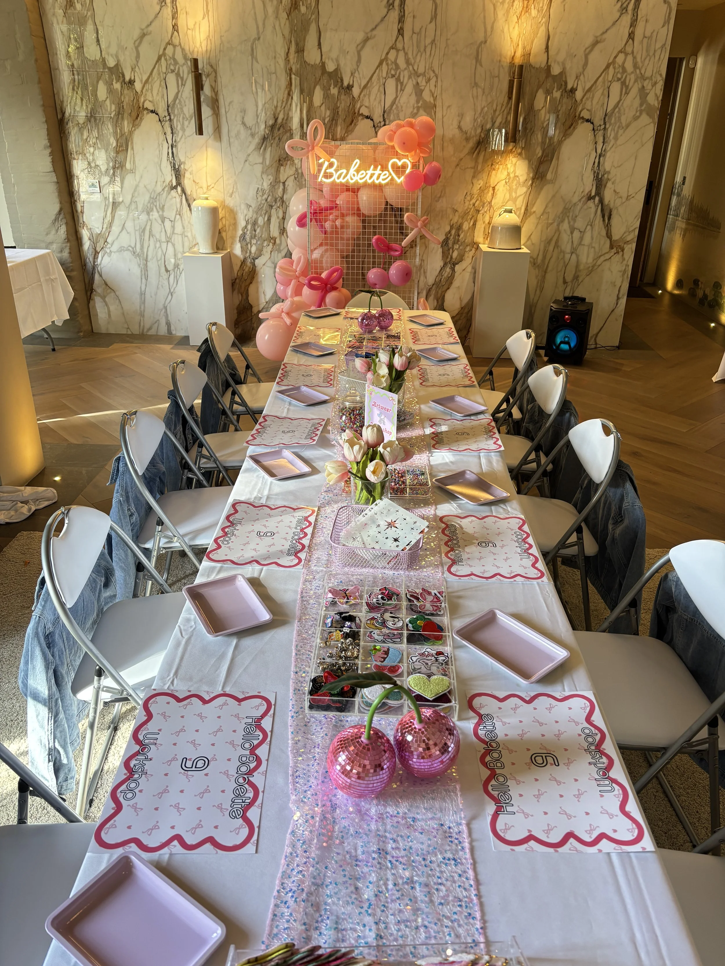 Table decorated for a birthday party with pink and white balloons, flowers, and themed decorations including a banner that says 'Babette'.