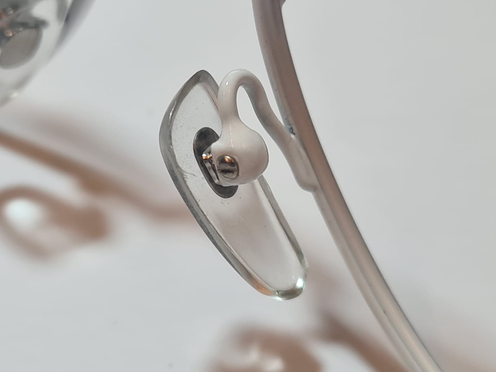Macro shot of a clear silicone nose pad and white pad arm on metal glasses frame