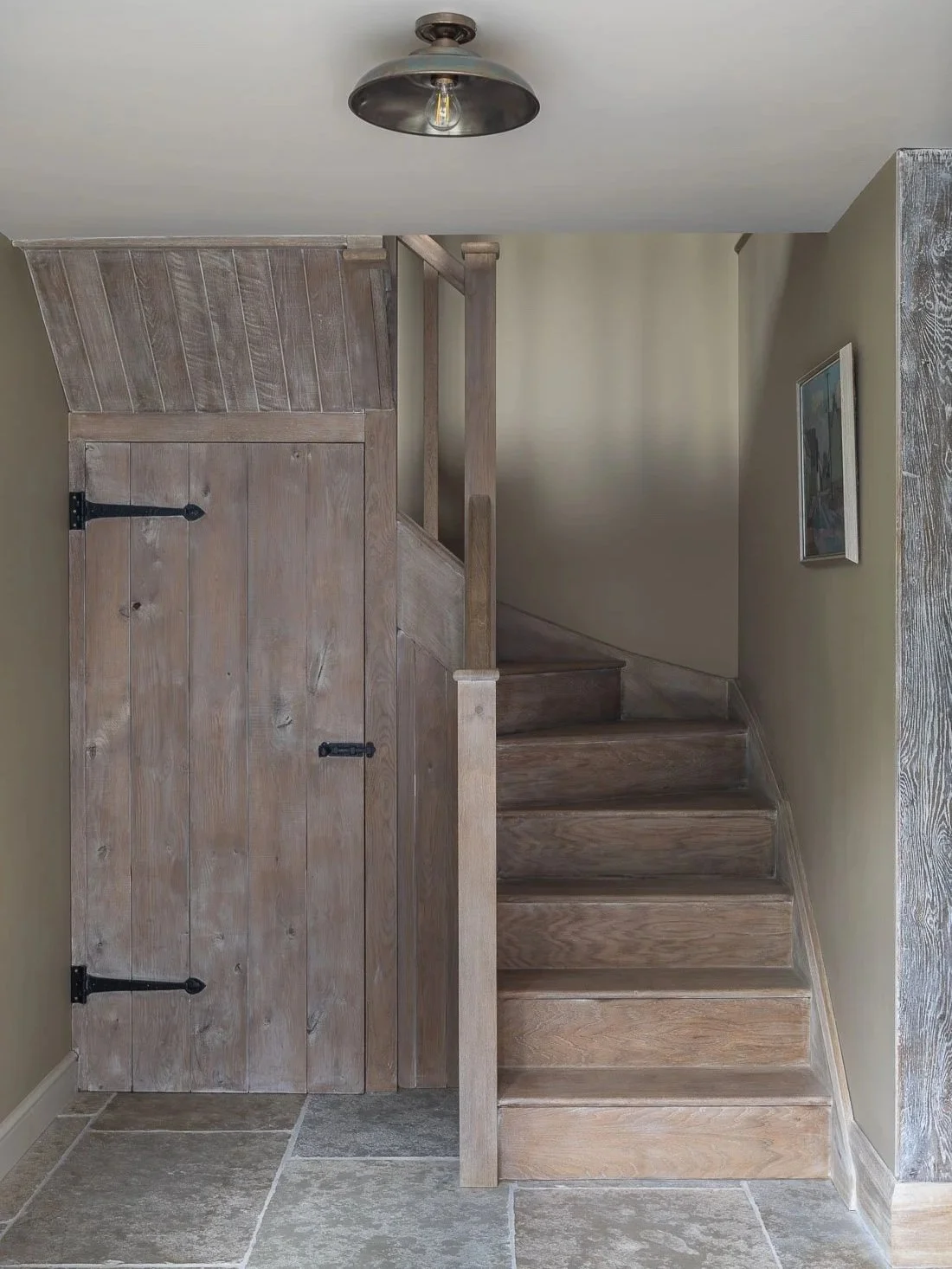 Period coach house outbuilding conversion restoration wooden staircase with storage and flagstone floor.