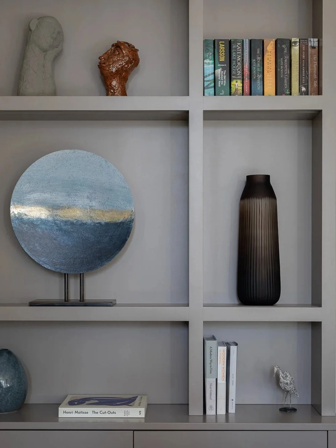 Detail of living room bespoke built-in bookcase shelving and storage with integrated lighting, neutral color.