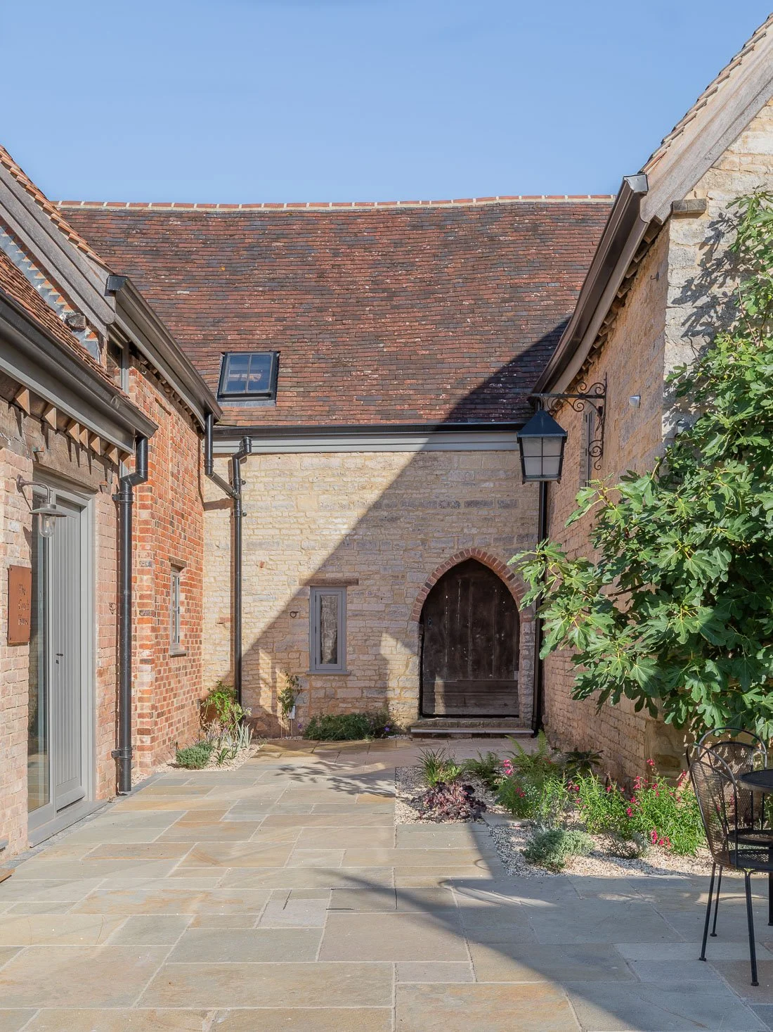 Period coach house outbuilding conversion restoration with landscaped patio courtyard.