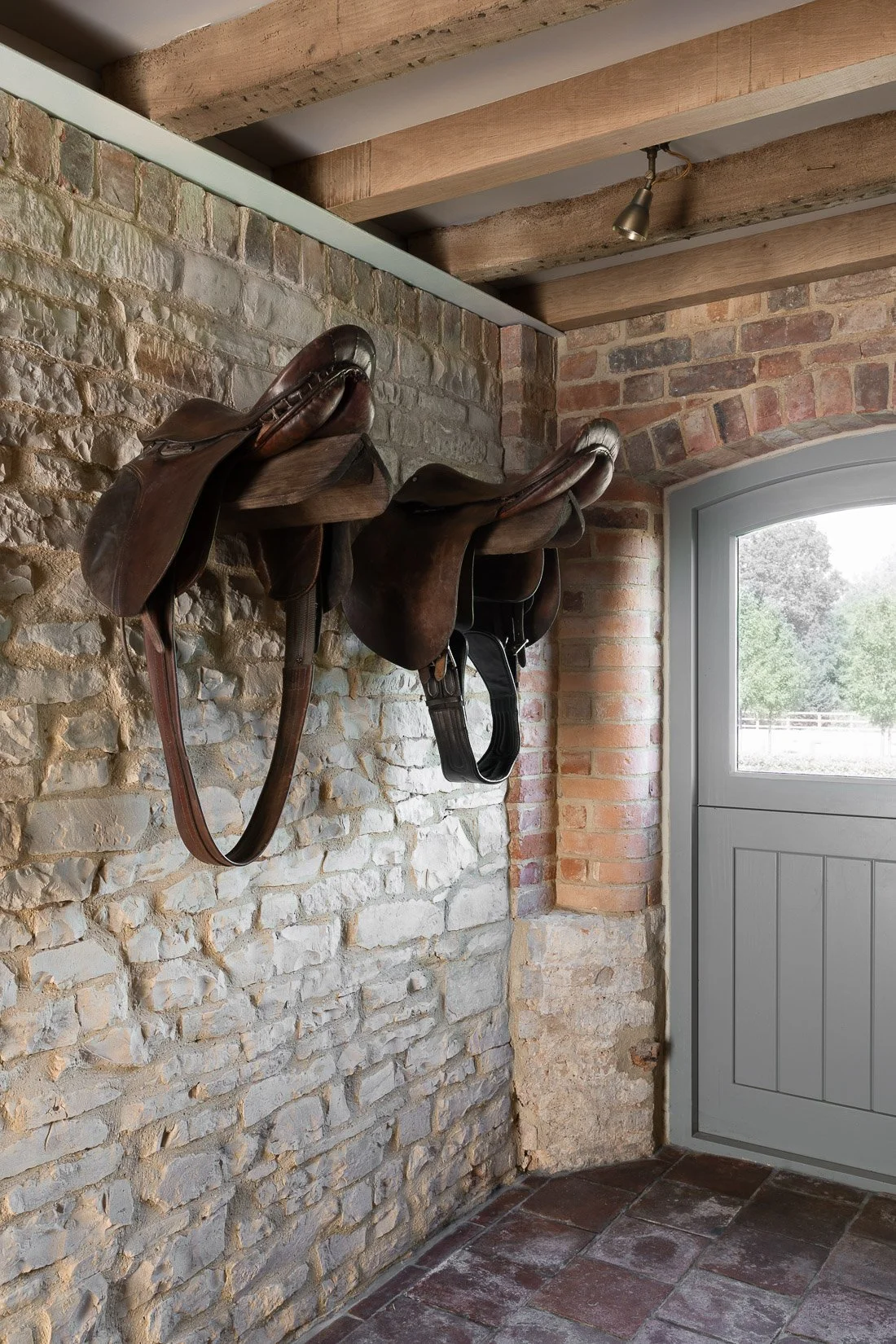 Period coach house outbuilding conversion restoration kitchen diner with exposed brickwork and decorative saddles.